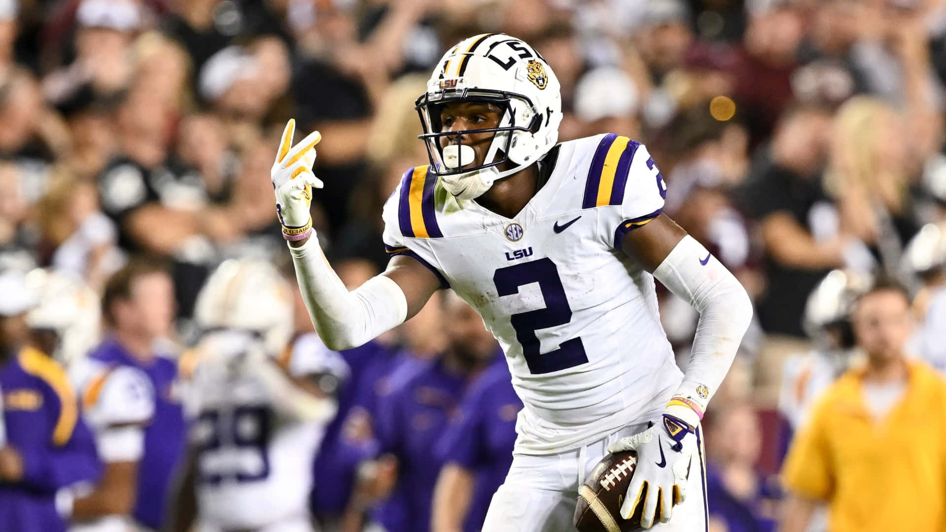  壁紙 — LSU 足球運動員二號在明亮的燈光下於擠滿觀眾的體育場慶祝達陣。