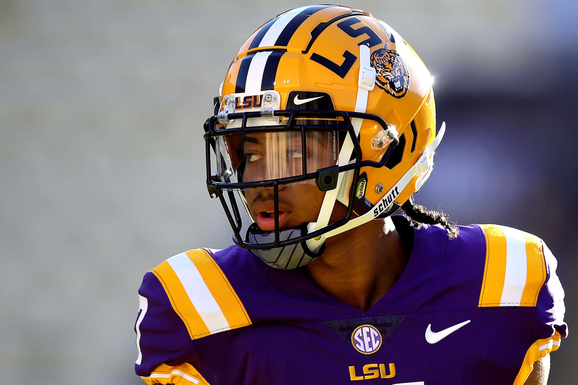 LSU 美式足球員身穿紫色和金色制服，頭戴老虎頭盔