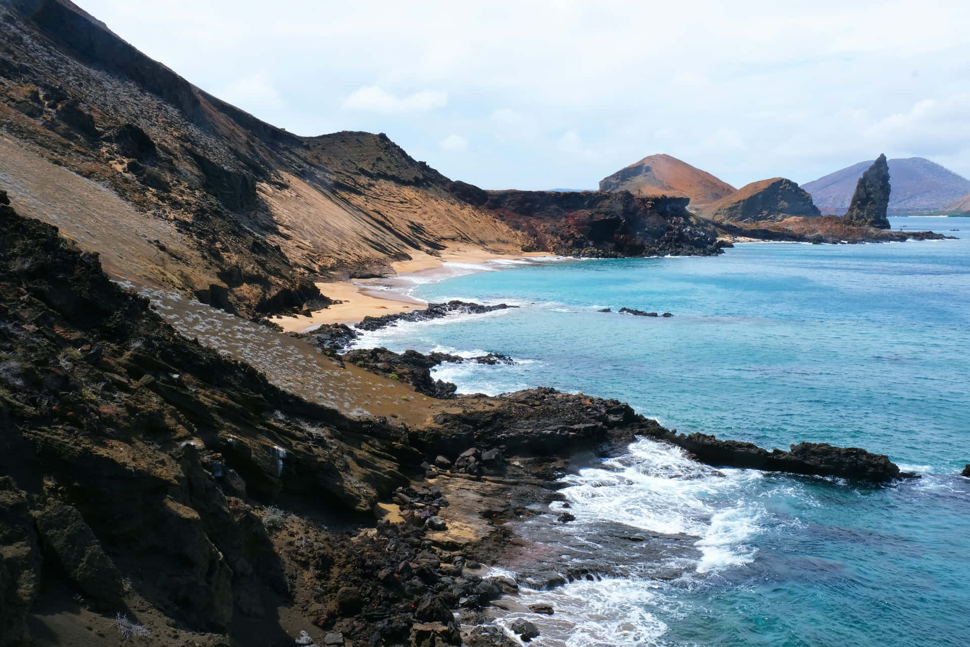  壁紙 — 在明亮的天空下，綠松石色的海浪拍打著崎嶇的火山懸崖，旁邊是一條狹窄的沙灘。