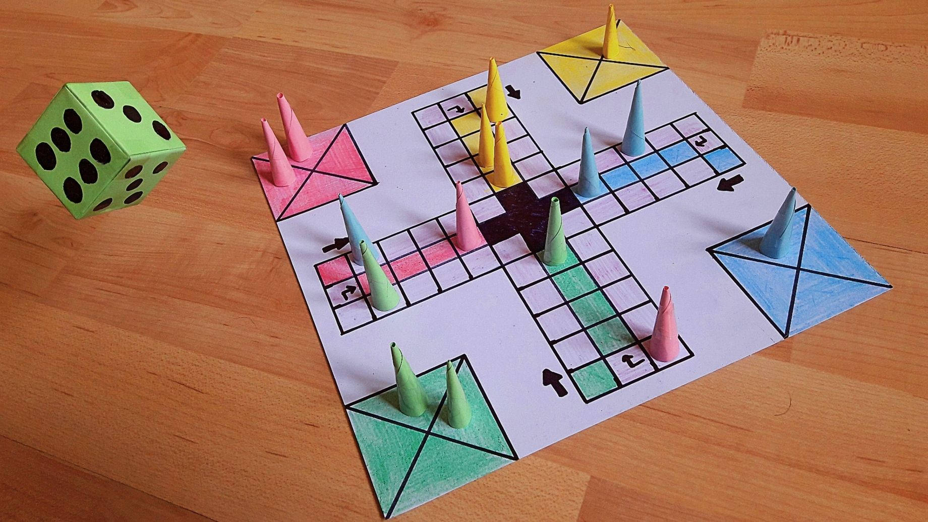 手工製作的Ludo遊戲，配有彩色錐體和綠色骰子，放在木地板上。