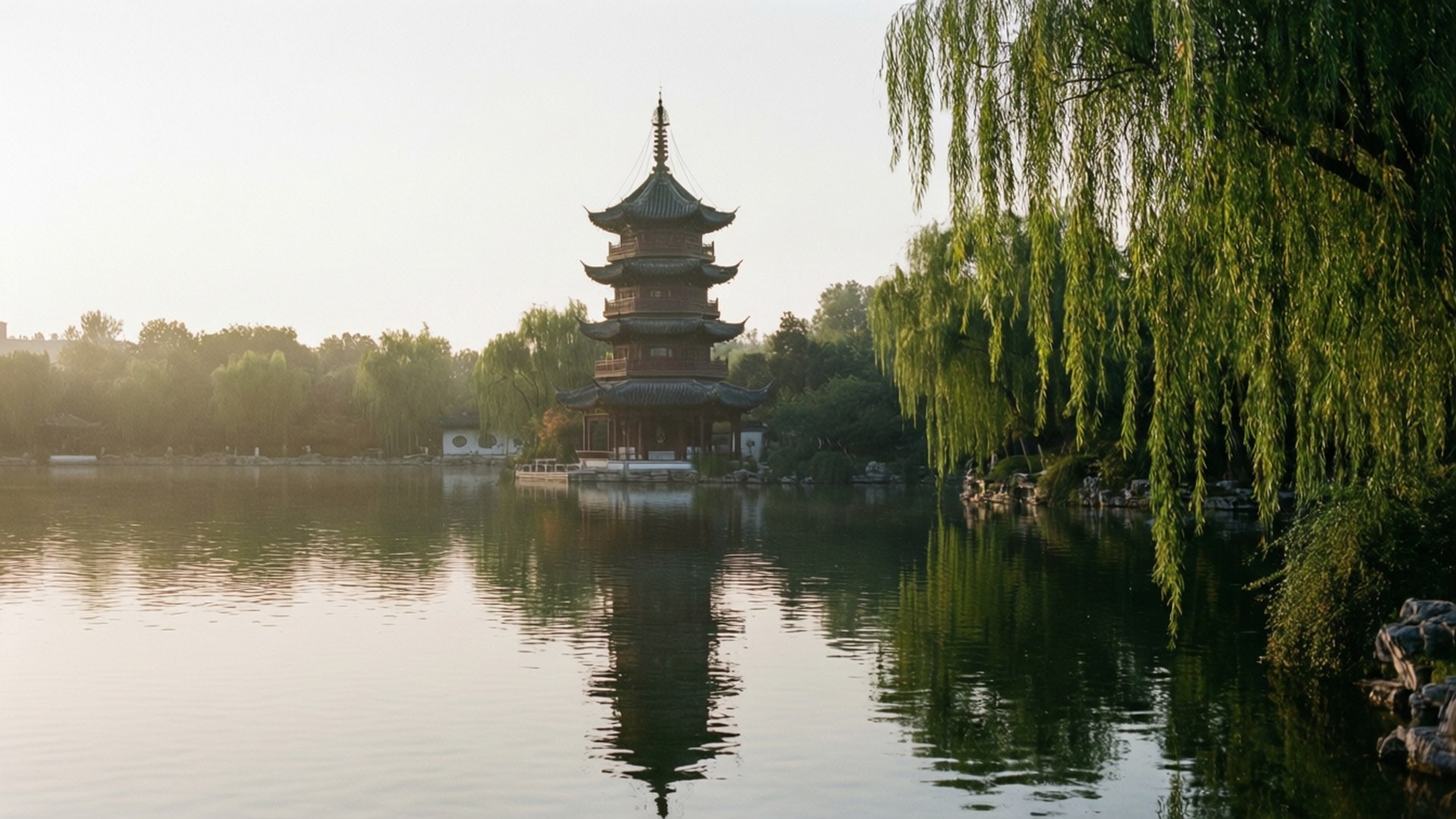 一座傳統的中國寶塔倒映在寧靜的湖中，周圍環繞著垂柳，在黎明時分。