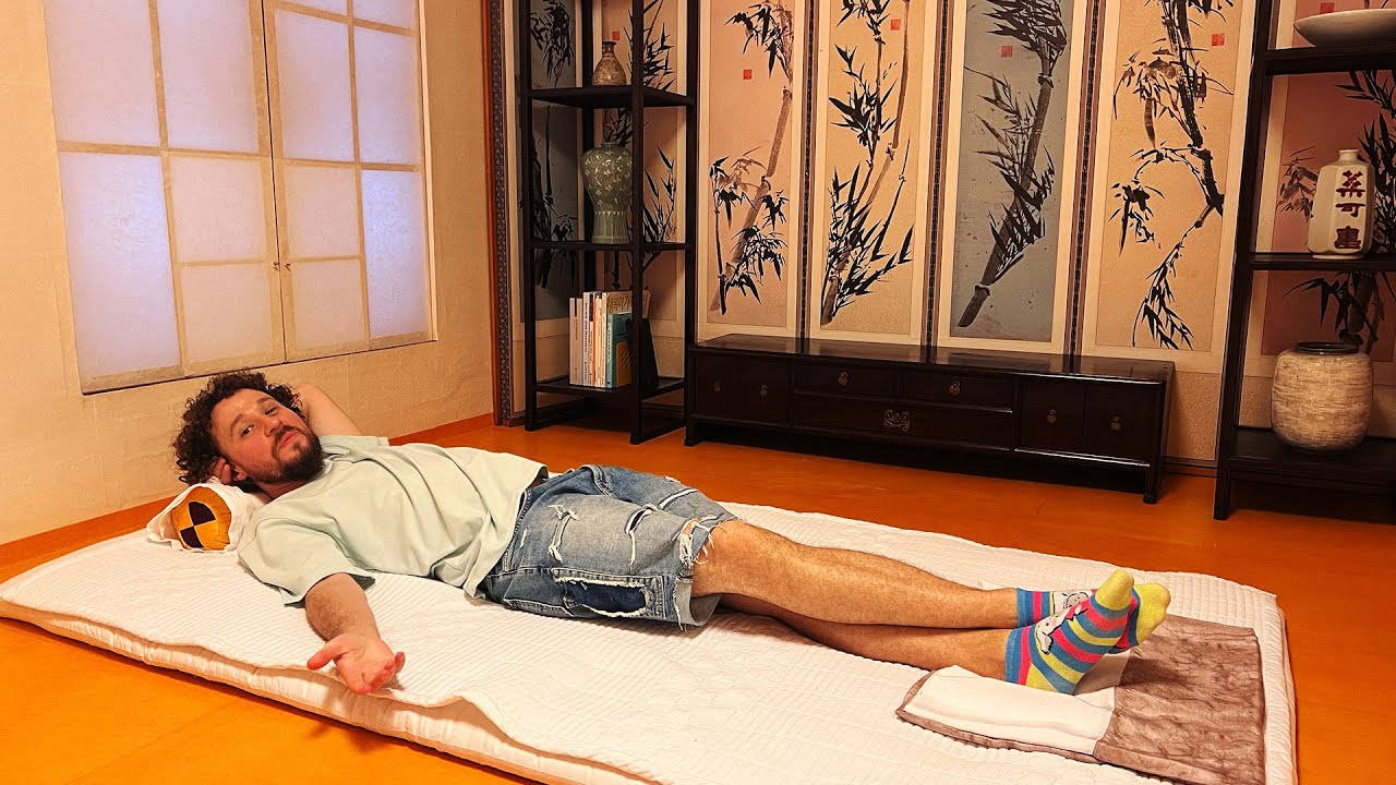 男子在傳統日式房間的榻榻米上休息，配有竹飾。