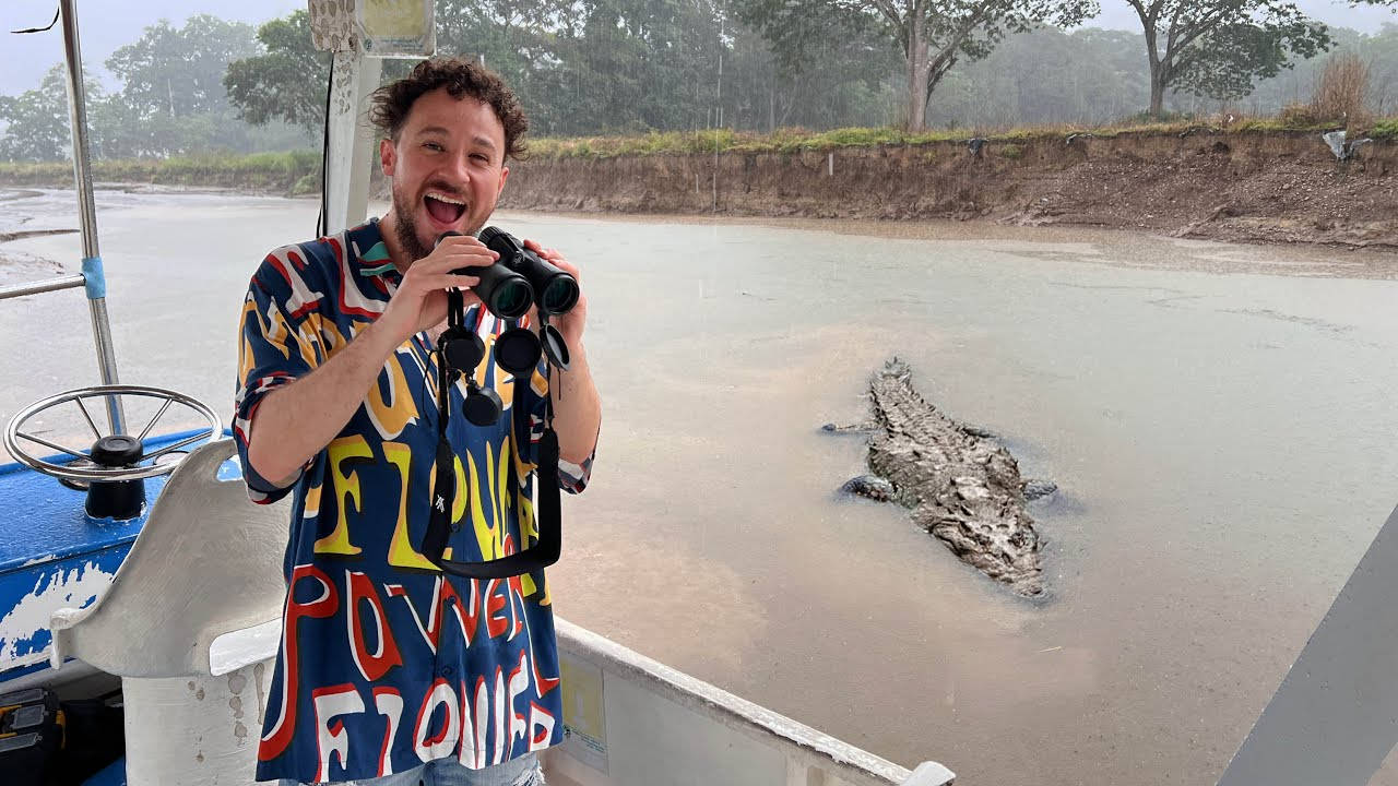 船上男子興奮地觀看泥河中的鱷魚