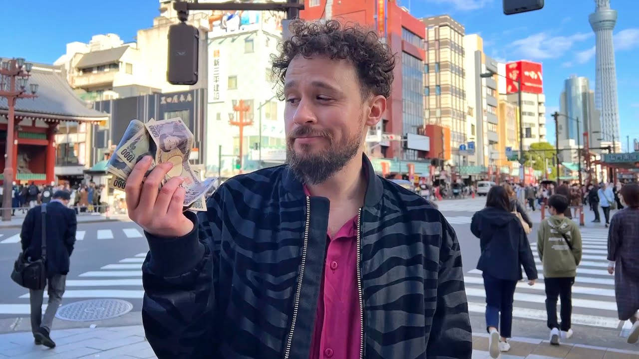 男子在繁忙的東京街道上手持日本日元紙幣，背景為晴空塔。