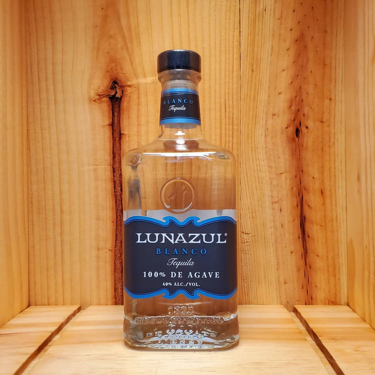 Lunazul Blanco 龍舌蘭酒瓶 壁紙 — 一瓶透明的Lunazul Blanco龍舌蘭酒，帶有藍色標籤，放在木架上，背景是溫暖的木鑲板。
