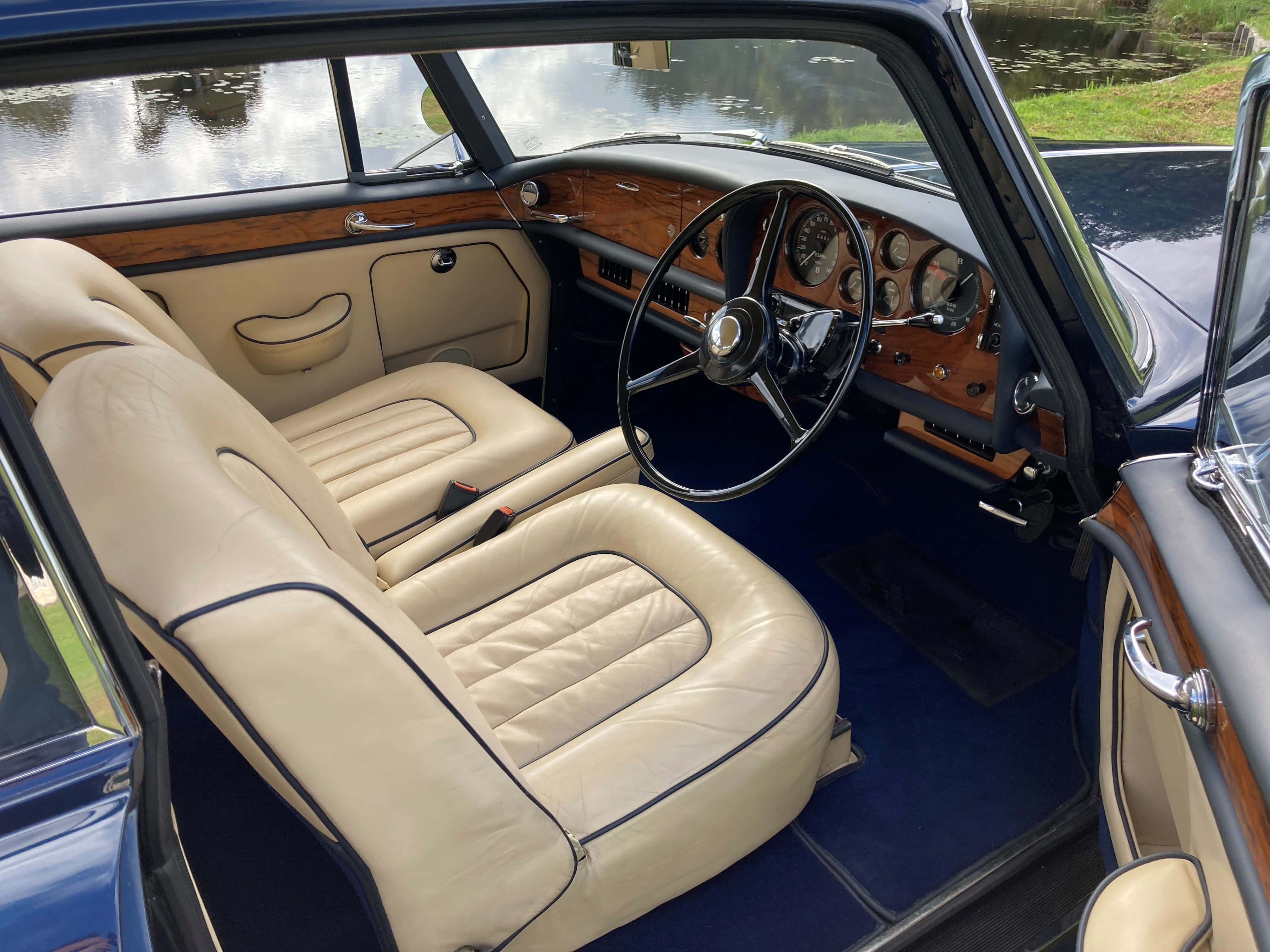 Bentley S3 桌布 壁紙 — 豪華復古車內飾，配奶油色皮革座椅和木質飾邊，俯瞰寧靜的池塘。