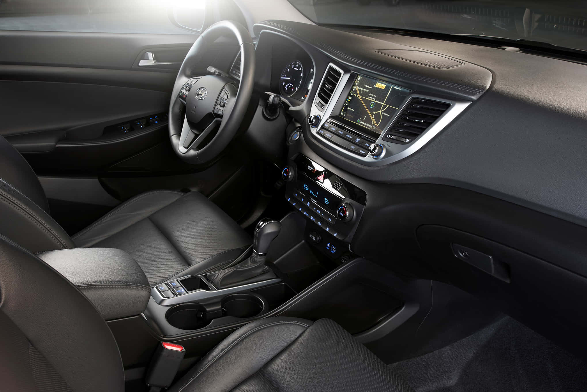 Hyundai Tucson 桌布 壁紙 — 豪華車內飾，配有黑色皮革座椅和時尚儀表板，由環境照明照亮。