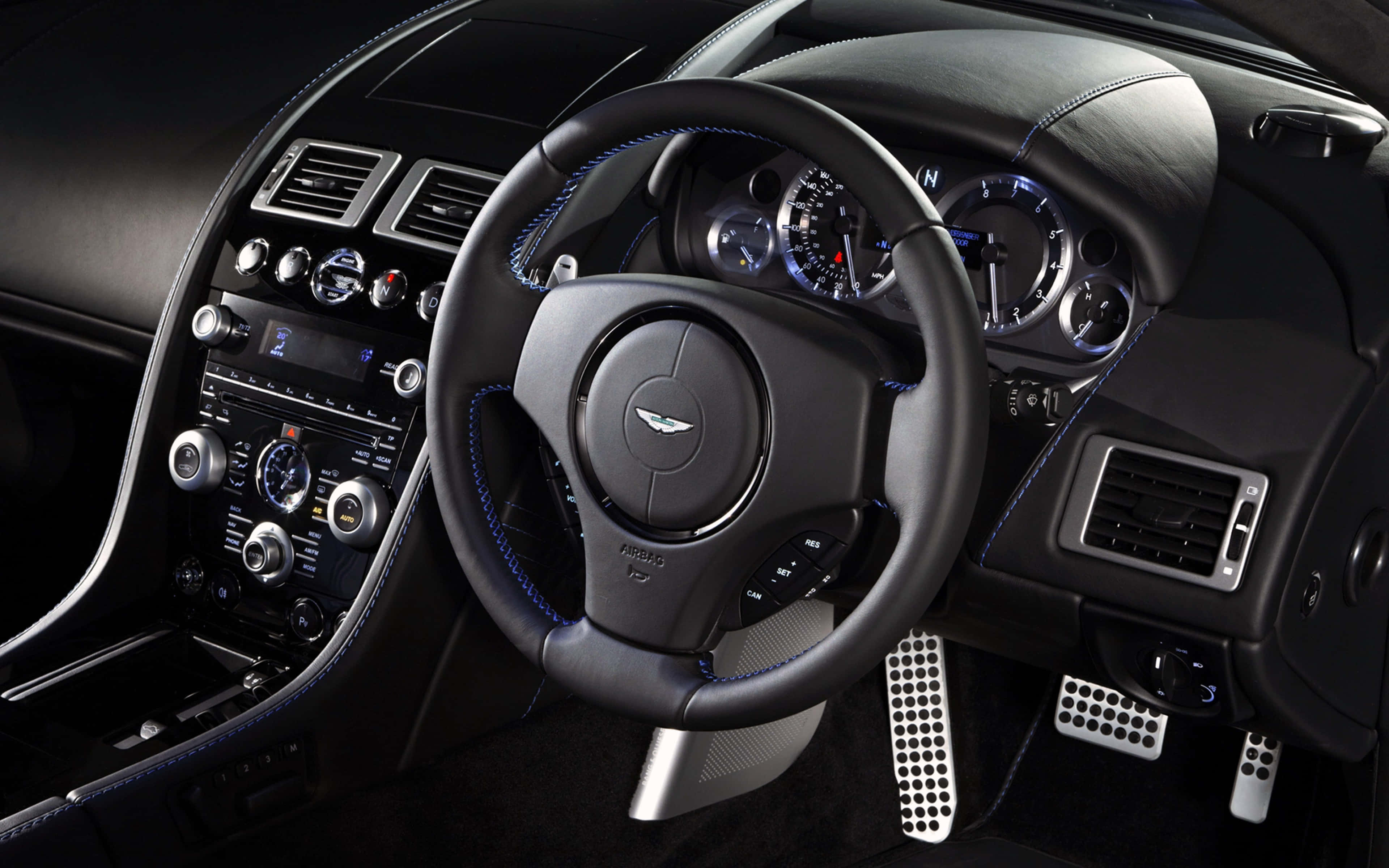 Steering Wheel 桌布 壁紙 — 豪華車內飾，配備黑色皮革方向盤、藍色縫線和發光儀表組。