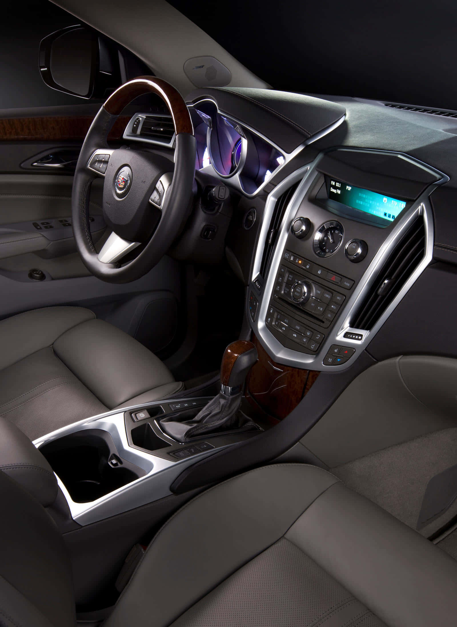 Cadillac Srx 桌布 壁紙 — 豪華車內飾，配備皮革座椅、木飾邊和發光數碼顯示屏，在昏暗的環境燈光下。
