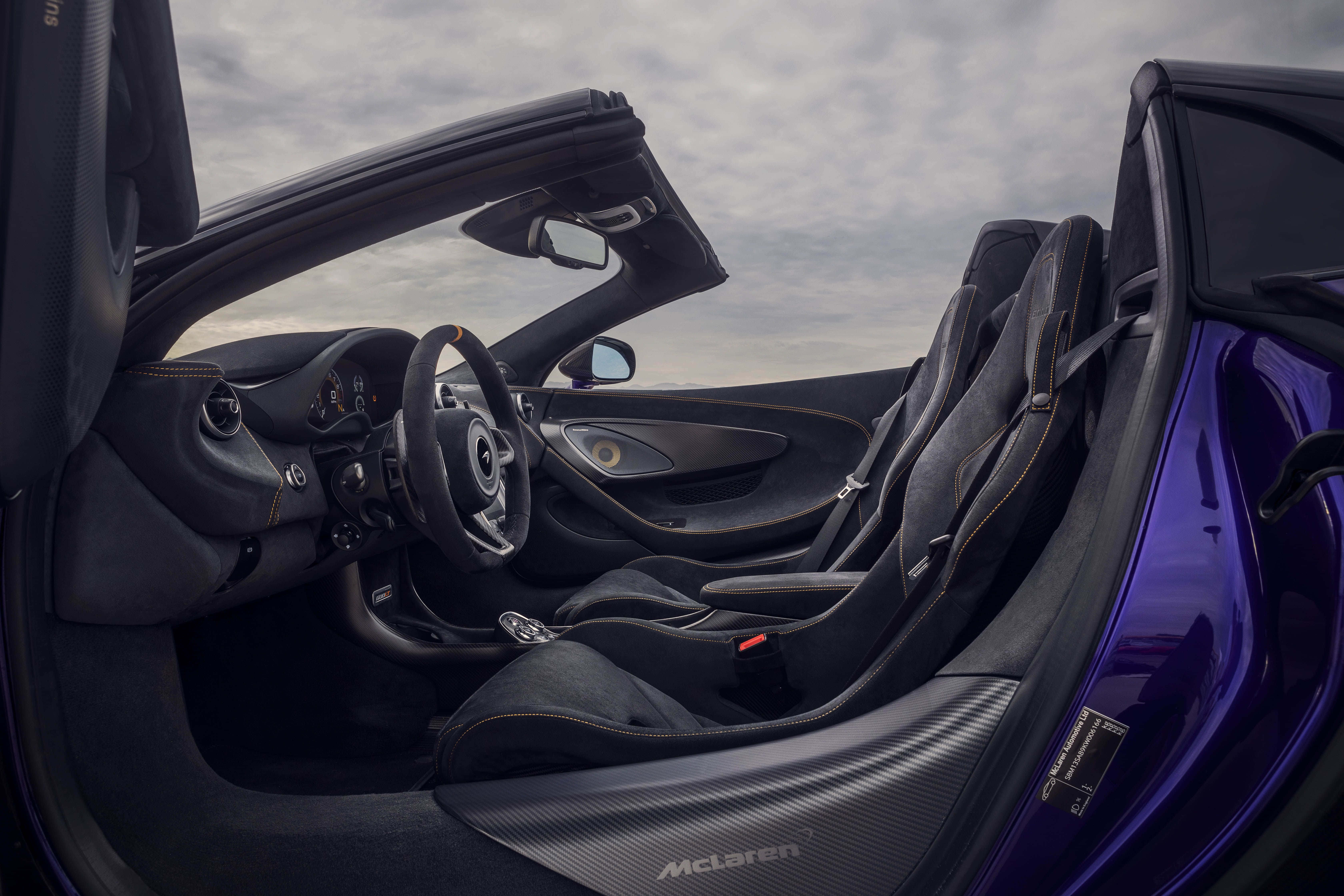 Mclaren 600lt Spider 桌布 壁紙 — 豪華跑車內飾，配備黑色皮革座椅和碳纖維飾邊，天空多雲。