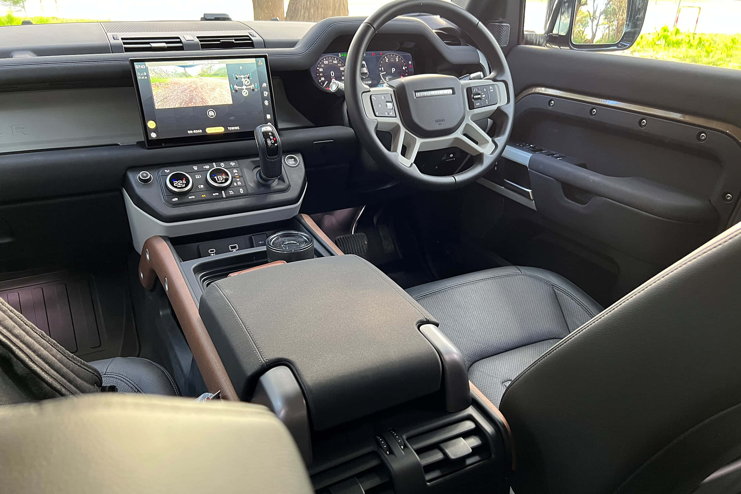 Land Rover Defender 桌布 壁紙 — 豪華SUV內飾，配備黑色真皮座椅、木質飾邊和顯示越野地形的數碼儀表板。