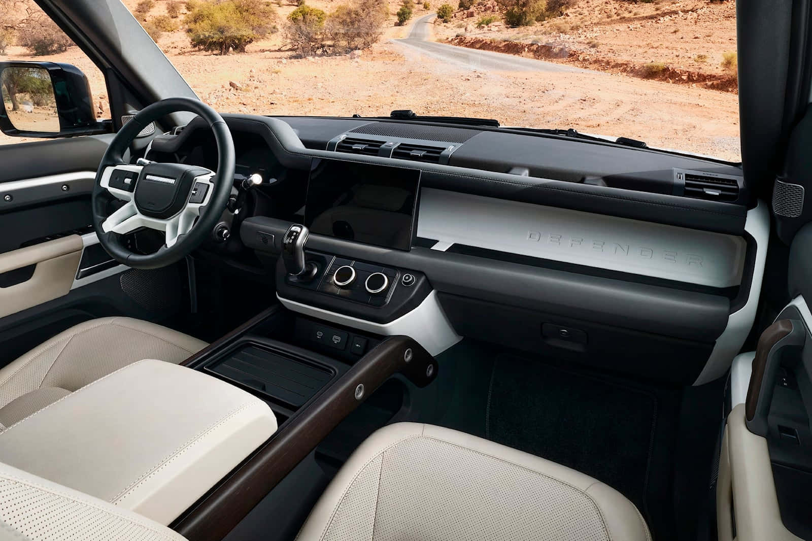 Land Rover Defender 桌布 壁紙 — 豪華SUV內飾，配以奶油色皮革座椅和木飾，俯瞰沙漠道路。