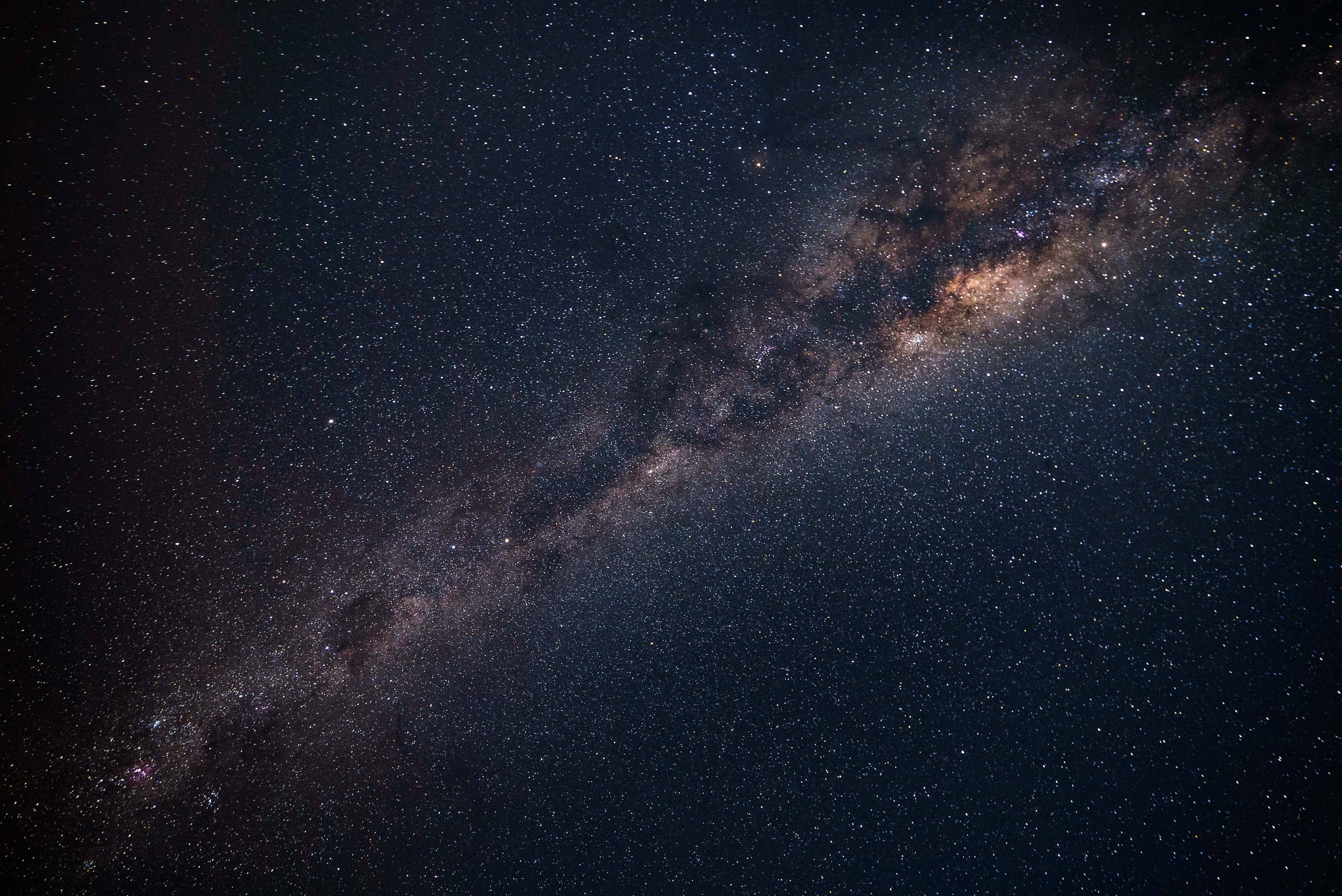 暗夜銀河 Mac 4K 壁紙 — 令人嘆為觀止的銀河系景觀，斜跨佈滿星星的夜空，帶有宇宙塵埃帶。