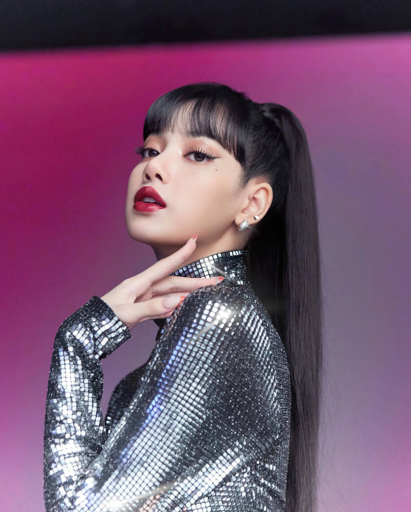 MAC Cosmetics Lisa BLACKPINK高清海報 壁紙 — 一位身穿閃亮銀色亮片上衣的女性，在粉紅和紫色漸變背景前擺姿勢，有著大膽的紅唇和高馬尾。