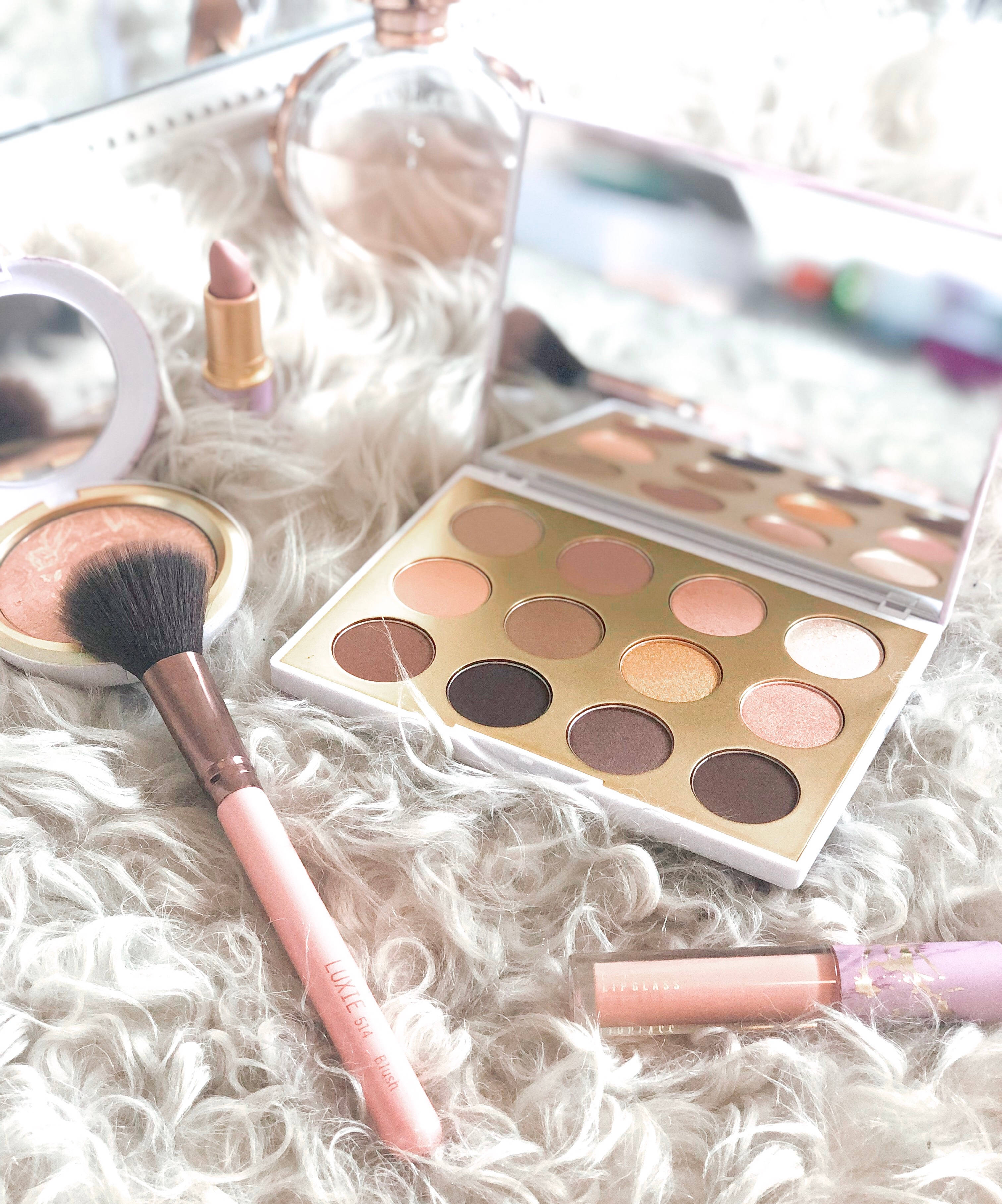 Mac Cosmetics 雪球冬季系列 壁紙 — 柔軟的粉紅色和金色化妝品系列放在毛絨白色地毯上，鏡面反射出產品。