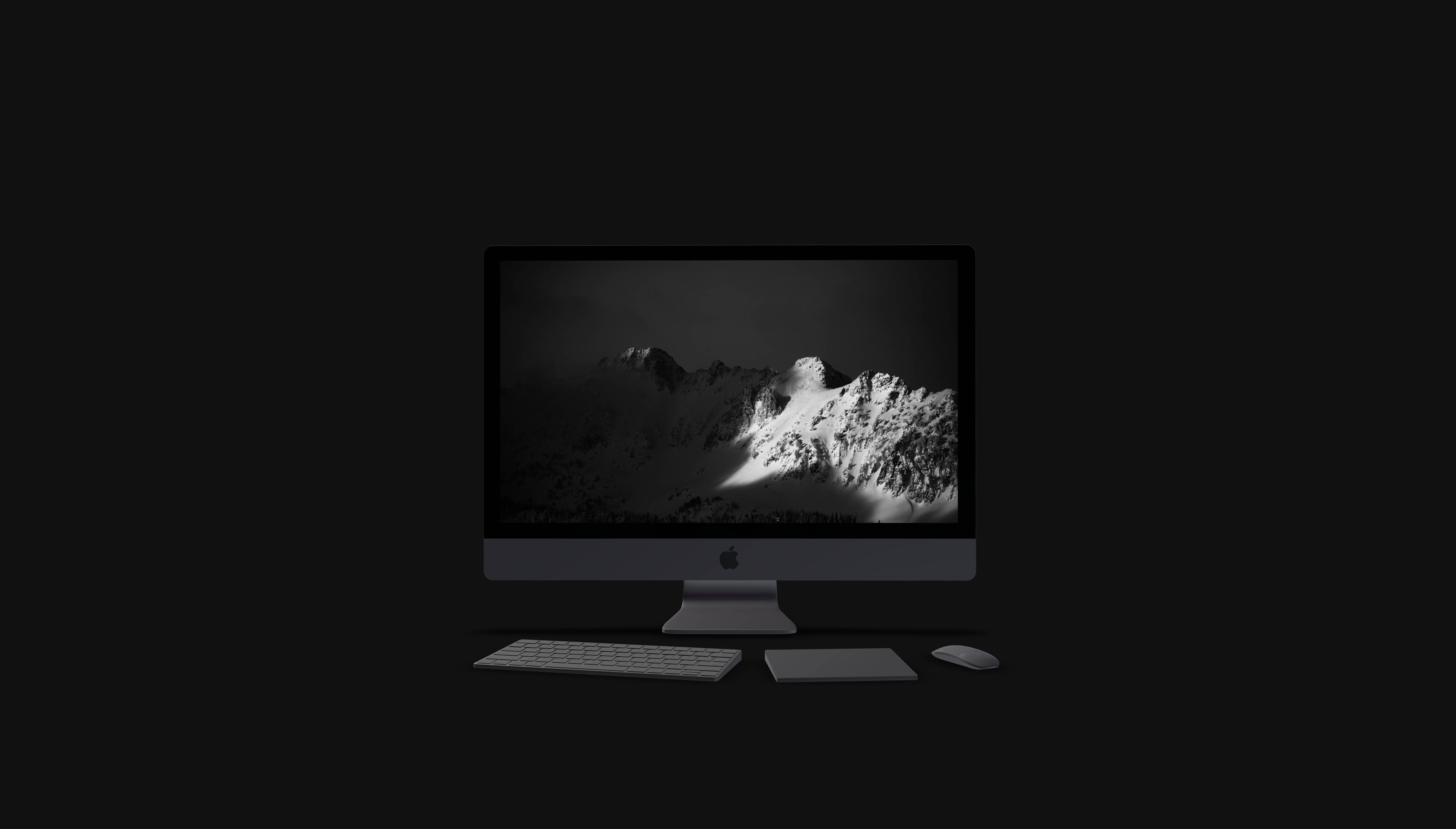 黑色MacBook 3D桌面 壁紙 — 一部時尚的iMac在極簡的深色背景上，顯示了黑暗天空下戲劇性的黑白山脈。