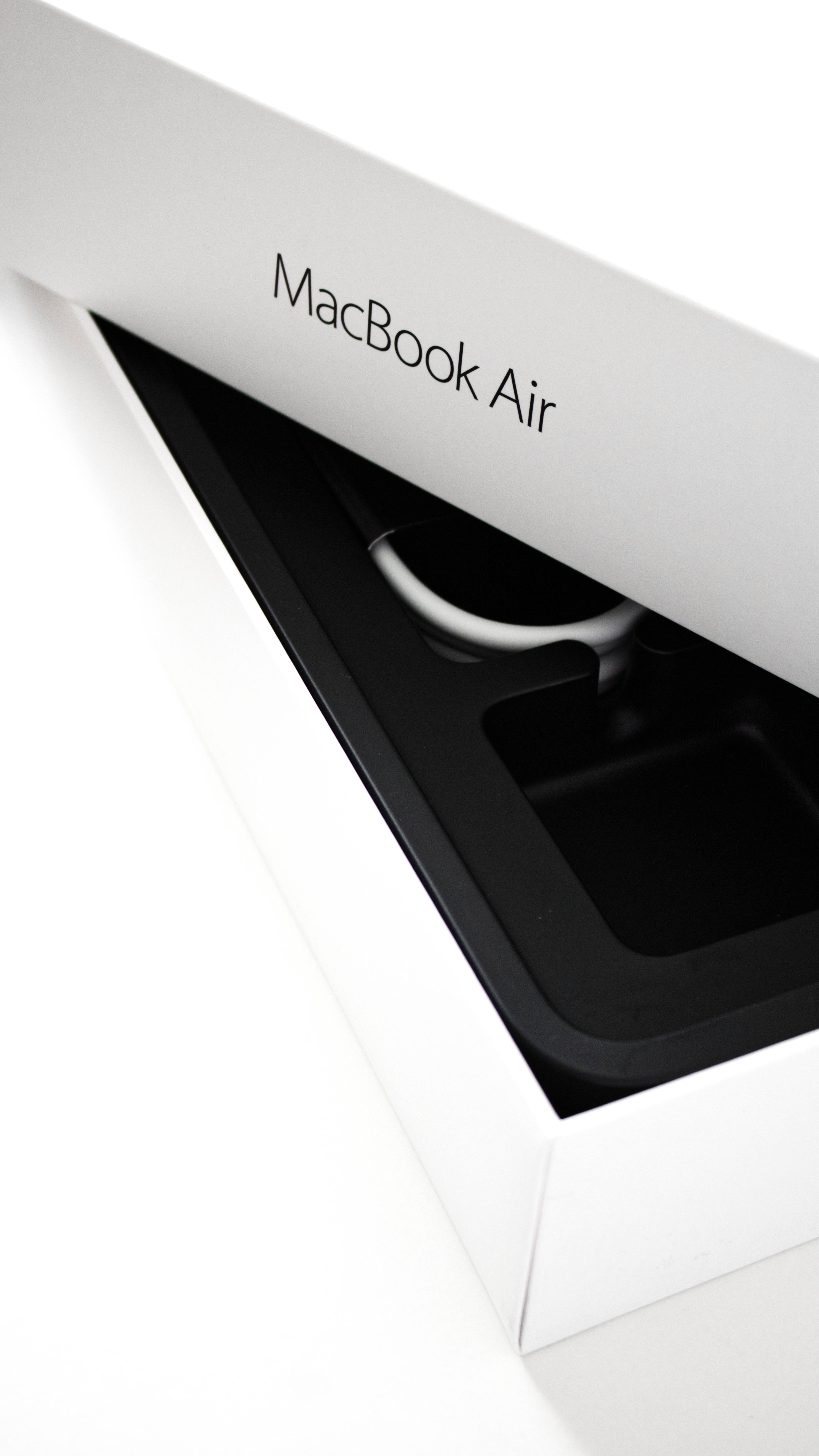 MacBook Air 2020包裝盒輕微開啟 壁紙 — 一部時尚的白色 MacBook Air 從其簡約的白色盒子中部分露出，展現黑色內部及銀色電線。