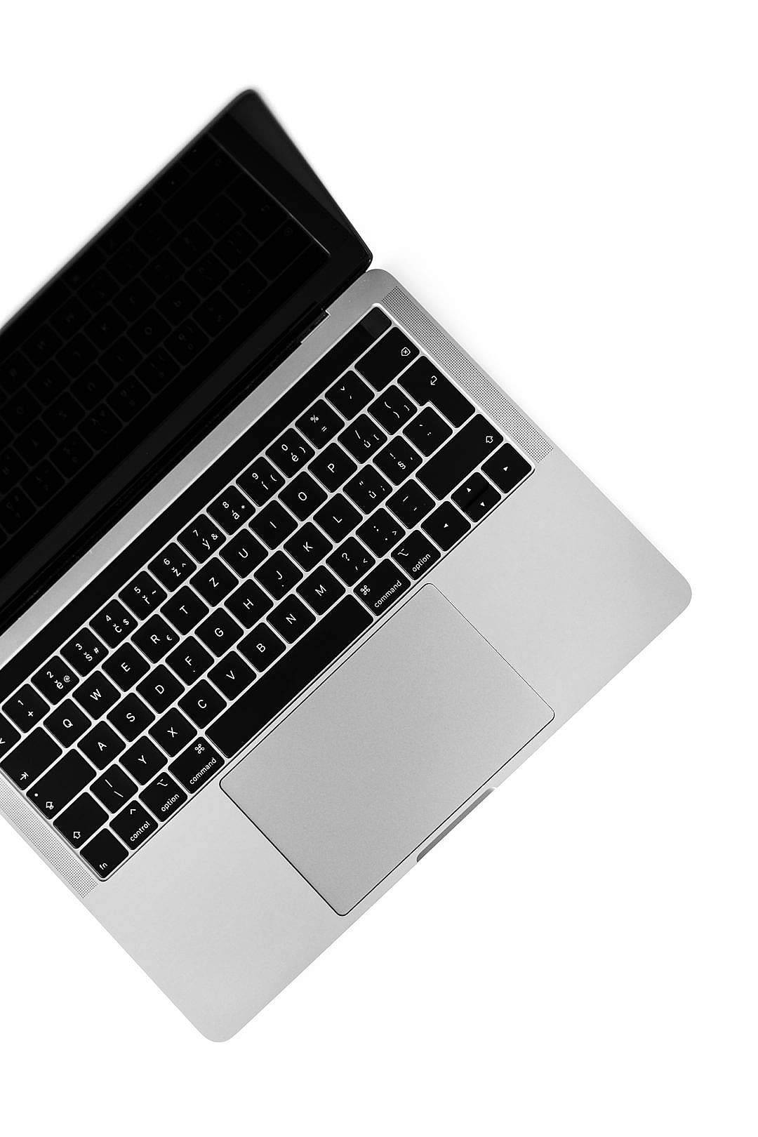 MacBook Air 2020 電話 壁紙 — 純白背景上，一部時尚銀色手提電腦的俯視圖，配備黑色鍵盤。