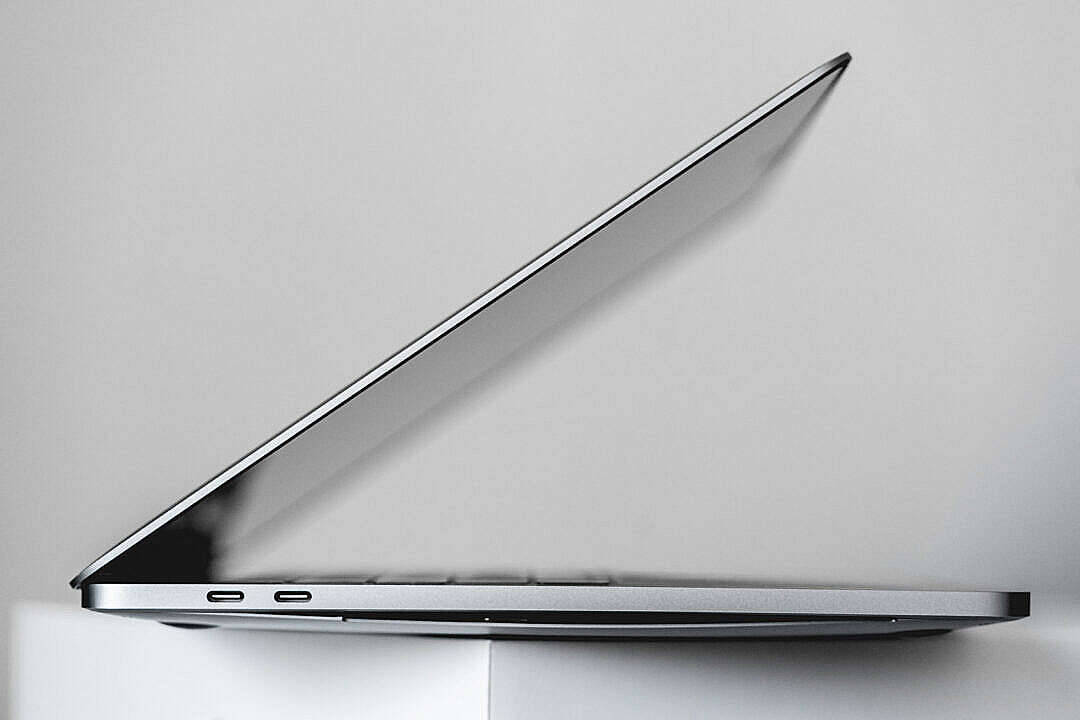 MacBook Air 2020 側面視角 壁紙 — 一部時尚的銀色手提電腦以銳角打開，襯托簡約的白色背景，展現其纖薄機身和現代設計。