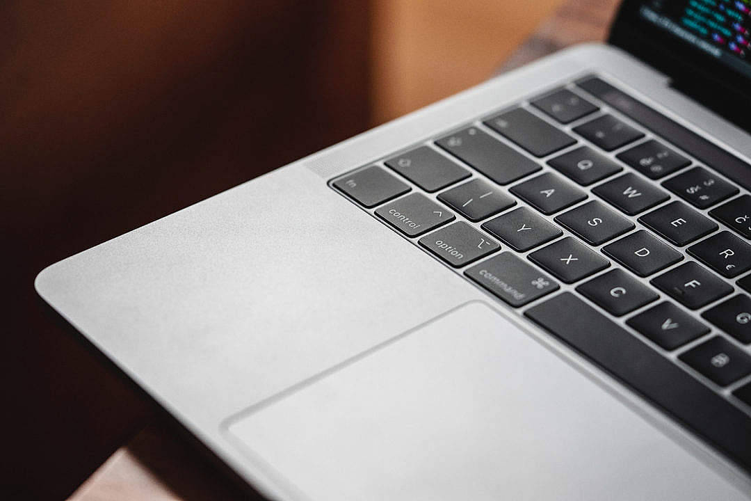 MacBook Air 2020 的近距離特寫 壁紙 — 銀色手提電腦鍵盤的特寫，黑色按鍵，發光屏幕顯示彩色代碼。