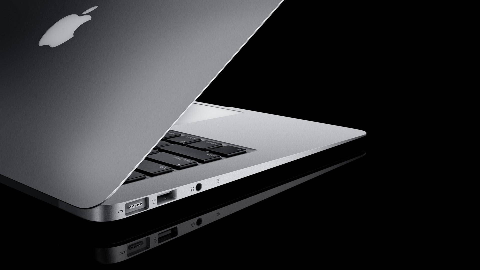 銀色MacBook手提電腦在黑色反光表面上顯示連接埠。