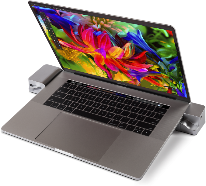 MacBook Pro 色彩螢幕與配件 壁紙 — 一部時尚的銀色手提電腦，屏幕上顯示充滿活力的抽象花卉壁紙，放置在簡約支架上，背景為黑色。