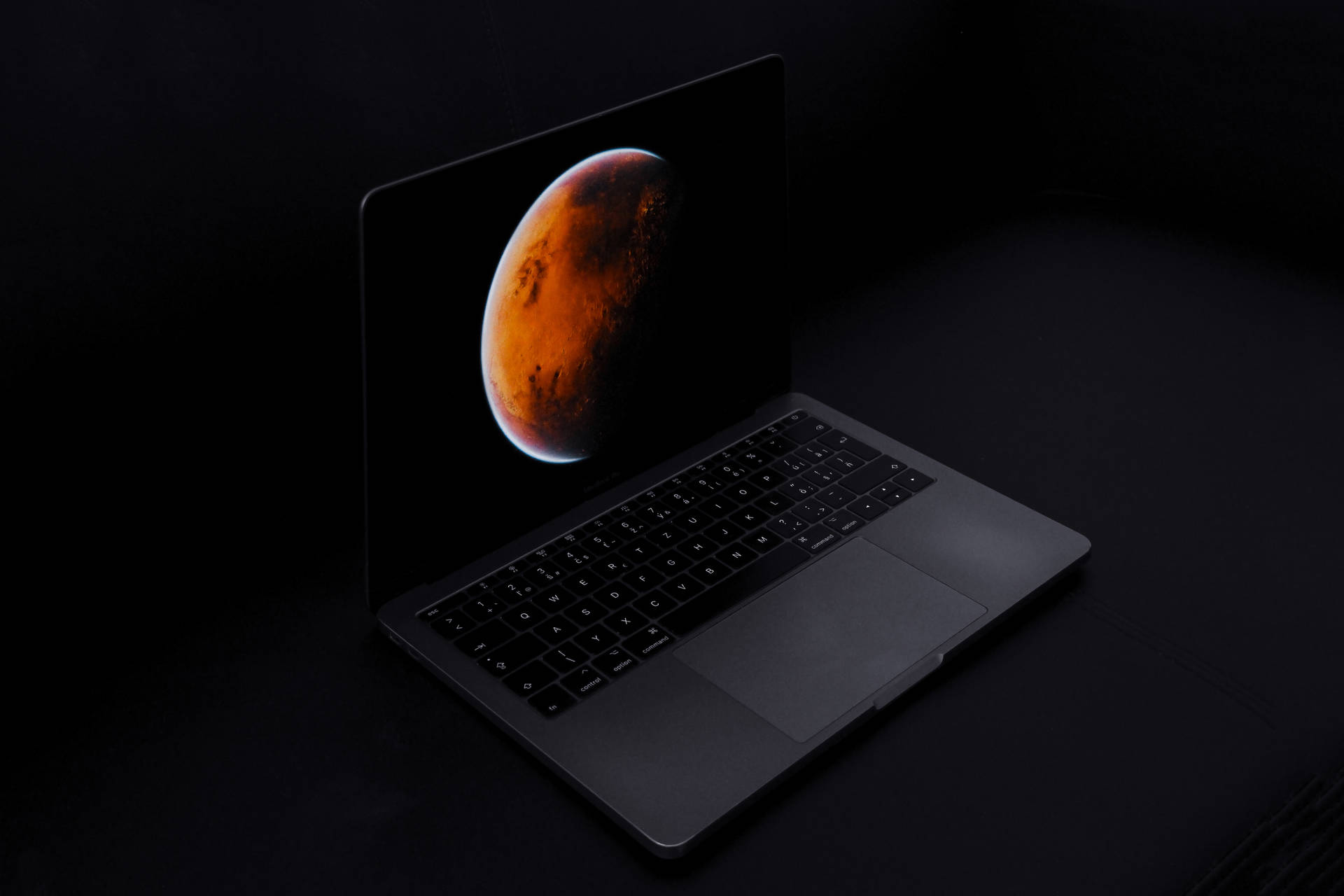 在黑暗極簡環境中，筆記型電腦螢幕顯示火星