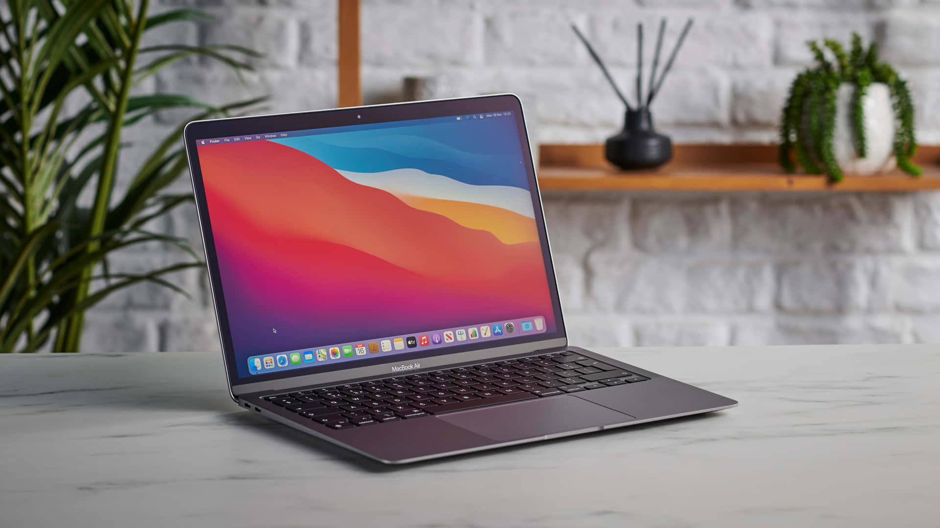 MacBook 的力量與風格 壁紙 — 一部時尚的銀色 MacBook Air 打開放在大理石檯面上，屏幕上閃耀著充滿活力的抽象壁紙。