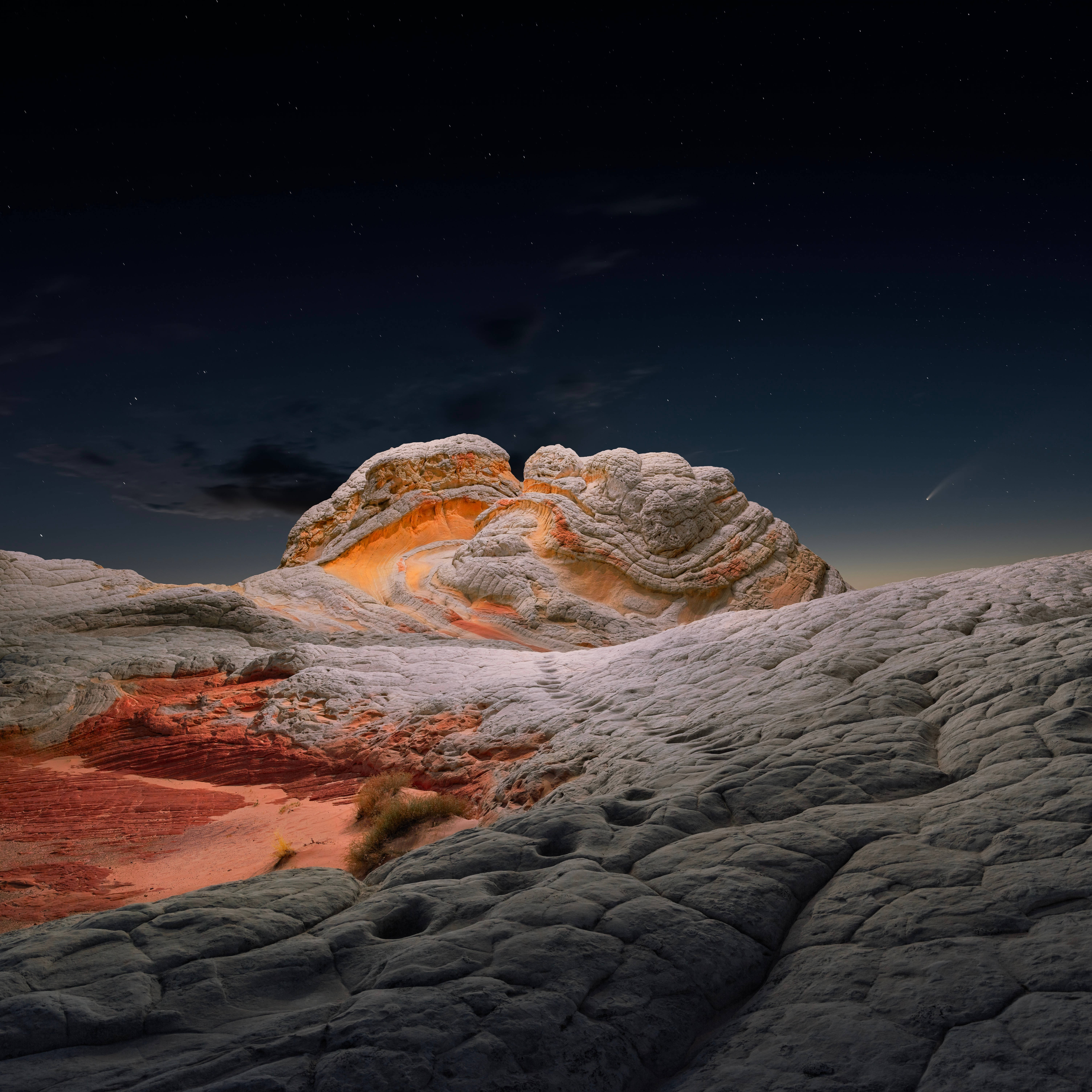 macOS Big Sur 岩石地貌 壁紙 — 星空之夜照亮了崎嶇的沙漠岩石形成，在黑暗的天穹下呈現出發光的橙色和白色條紋。