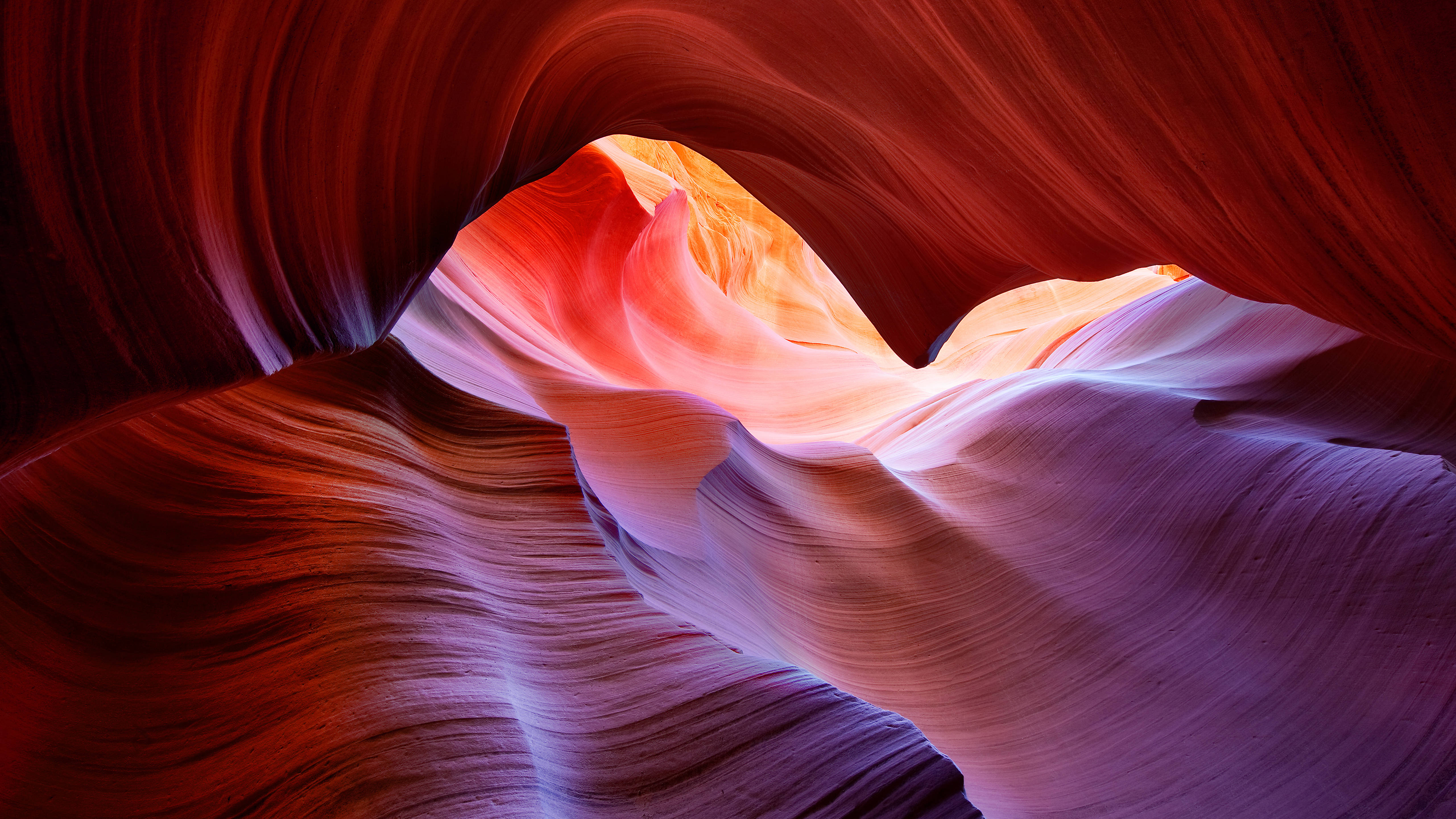 macOS Big Sur 紅崖風景 壁紙 — 令人驚嘆的自然岩層，流動的紅色、橙色和紫色色調，被柔和陽光照射。
