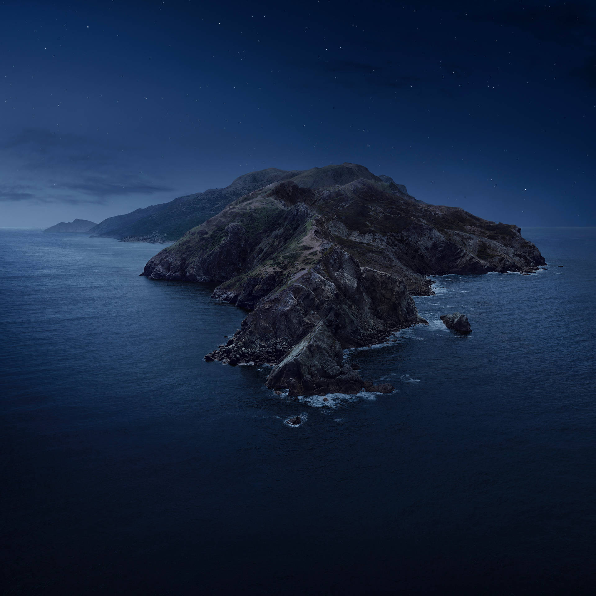 在繁星點點的夜空下，海洋中的一個岩石島嶼。