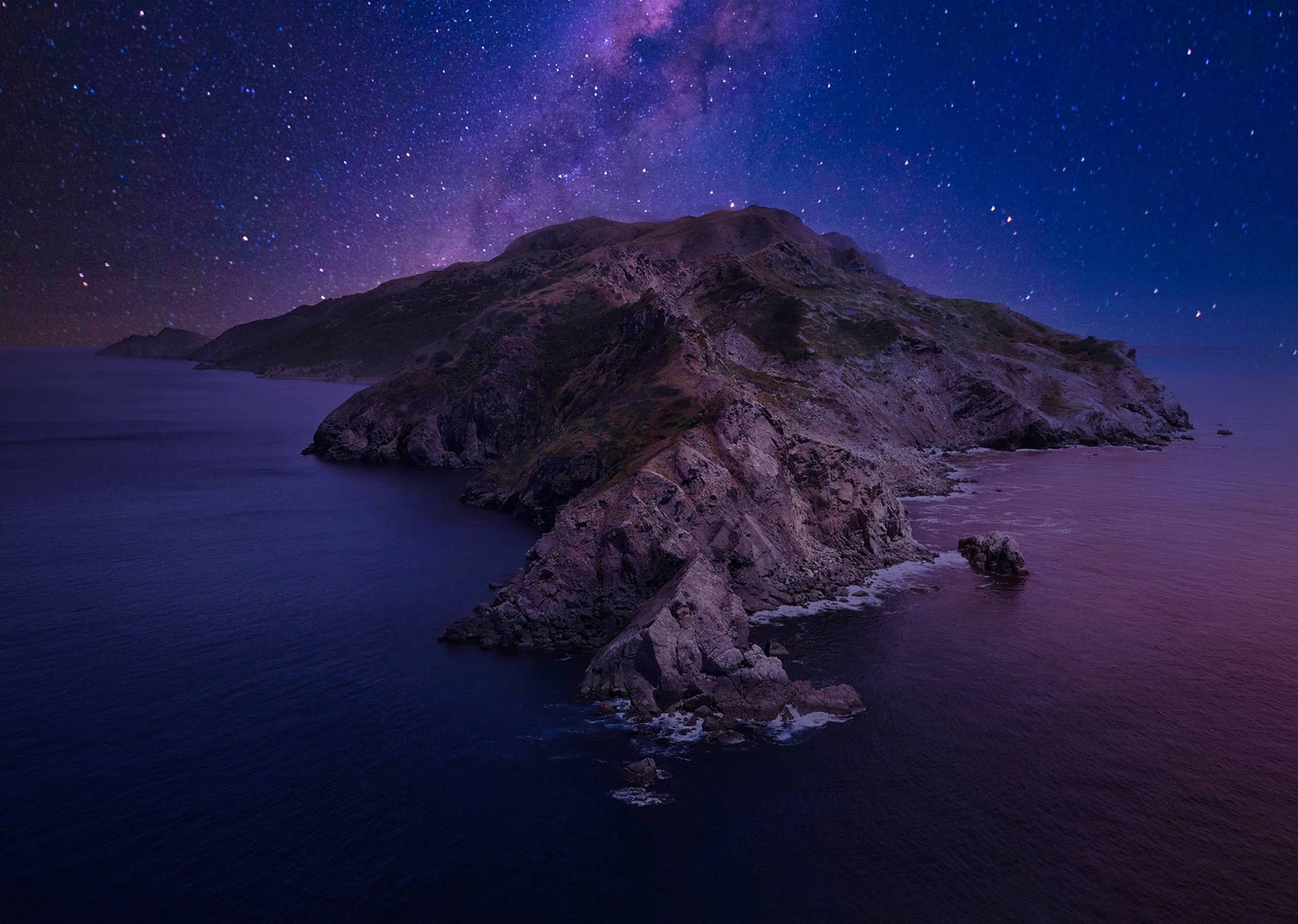 macOS Catalina 星空夜景 壁紙 — 一座崎嶇的島嶼從深紫色的海水中升起，星空下有一條發光的紫色銀河。