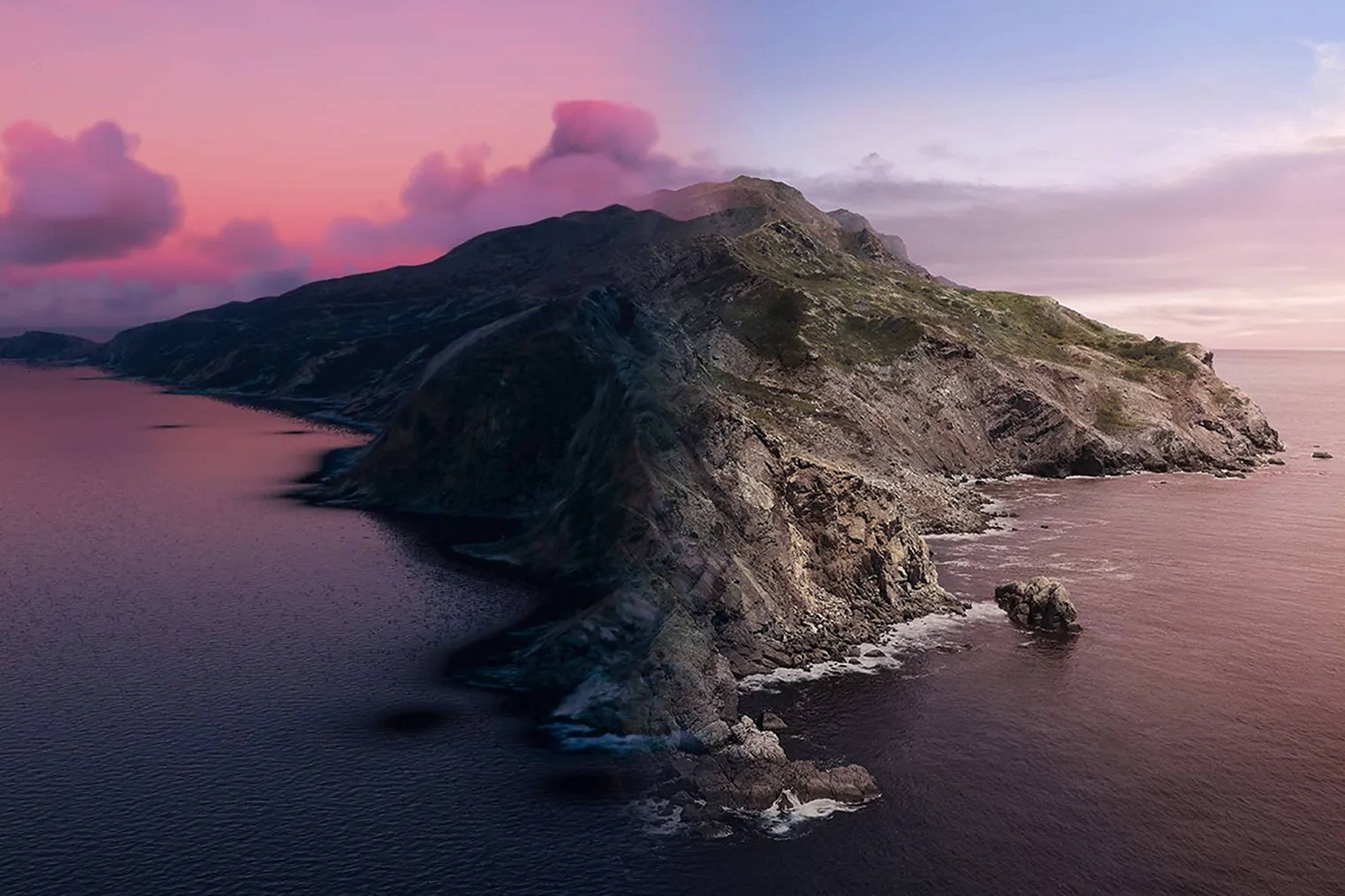 macOS Catalina 梯度天空 壁紙 — 崎嶇的海岸懸崖沐浴在粉紅色和紫色的暮色中，海浪拍打著岩石海岸。