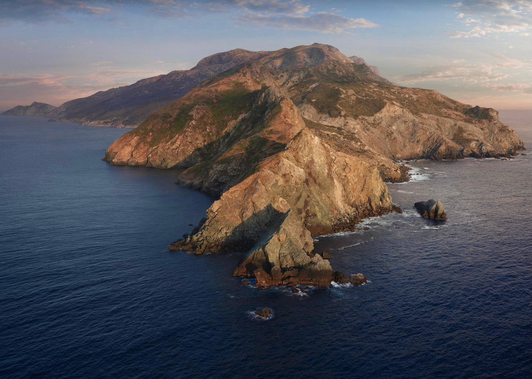 日落時分，深藍海洋環繞著崎嶇岩石島嶼，懸崖與稀疏綠意。