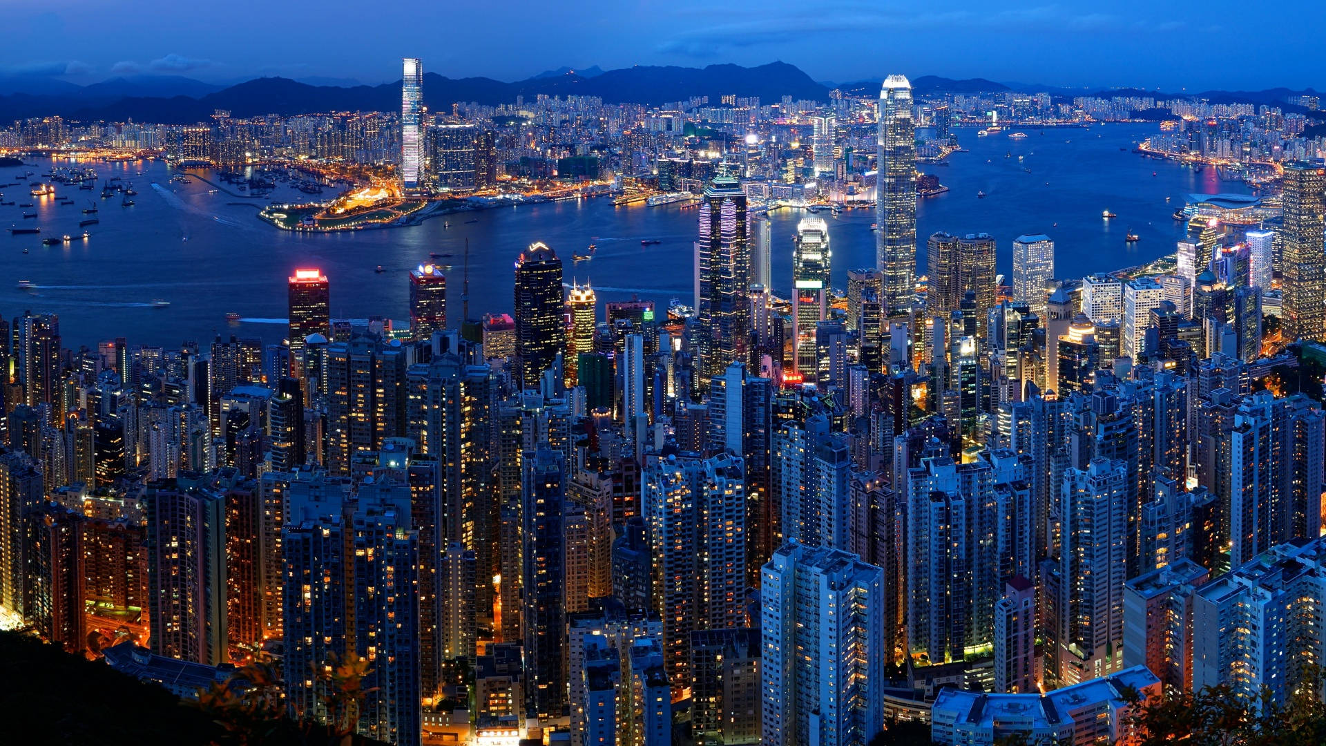 黃昏時分的香港城市景觀，燈火通明的摩天大樓與港灣水面。