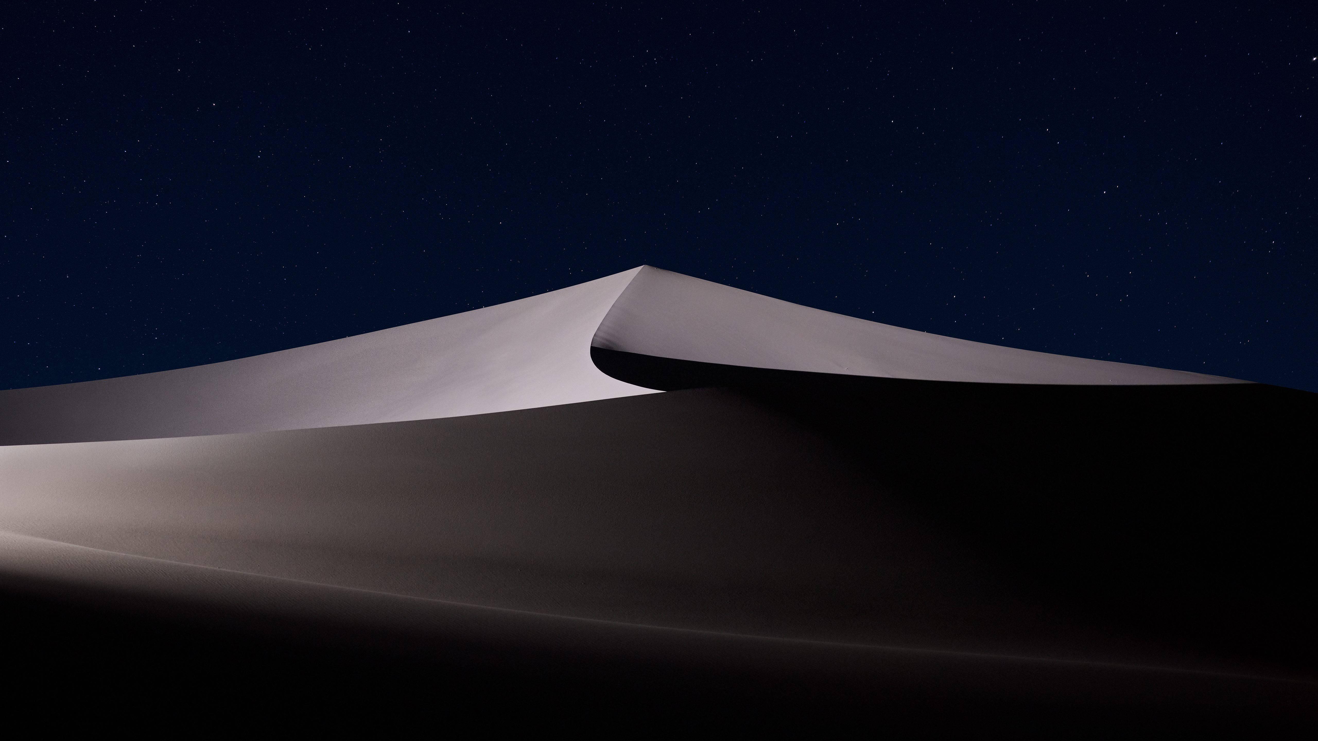 黑白沙漠MacOS 壁紙 — 在繁星點點的夜空下，柔和的月光勾勒出平靜沙漠沙丘的流暢曲線。