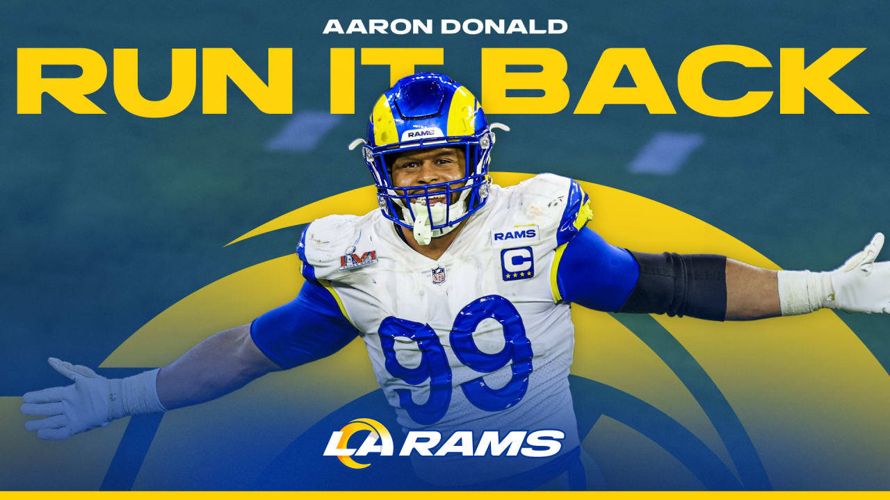 Madden 99俱樂部 洛杉磯公羊隊 阿隆·唐納德 壁紙 — Aaron Donald 身穿洛杉磯公羊隊球衣，在充滿活力的藍黃色背景上張開雙臂慶祝。