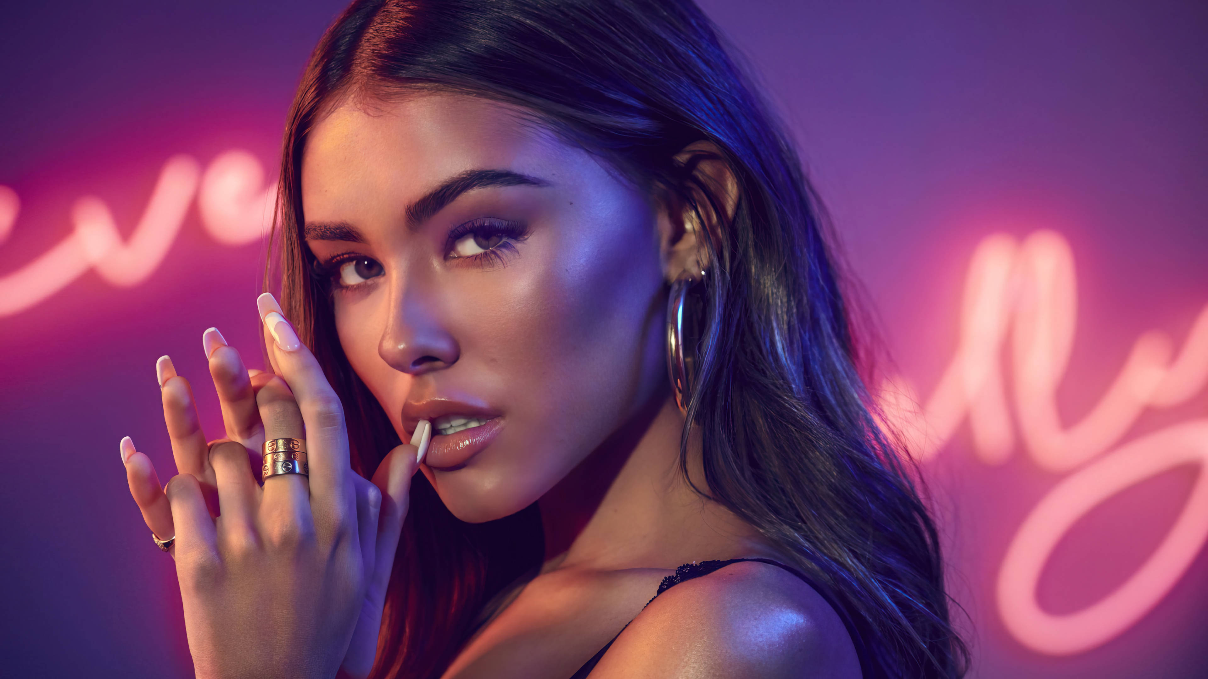 酷女孩 Madison Beer 壁紙 — 一位擁有長長黑髮和誇張妝容的女性，在充滿活力的夜店環境中，於發光的粉紅色霓虹燈牌前擺姿勢。