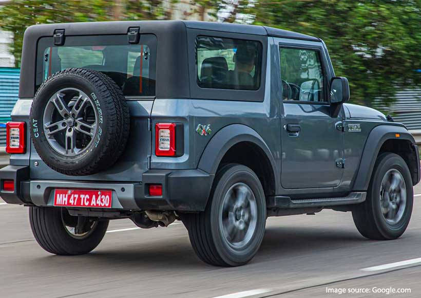 灰色鈴木 Jimny SUV 在鋪砌道路上行駛，周圍綠意盎然。