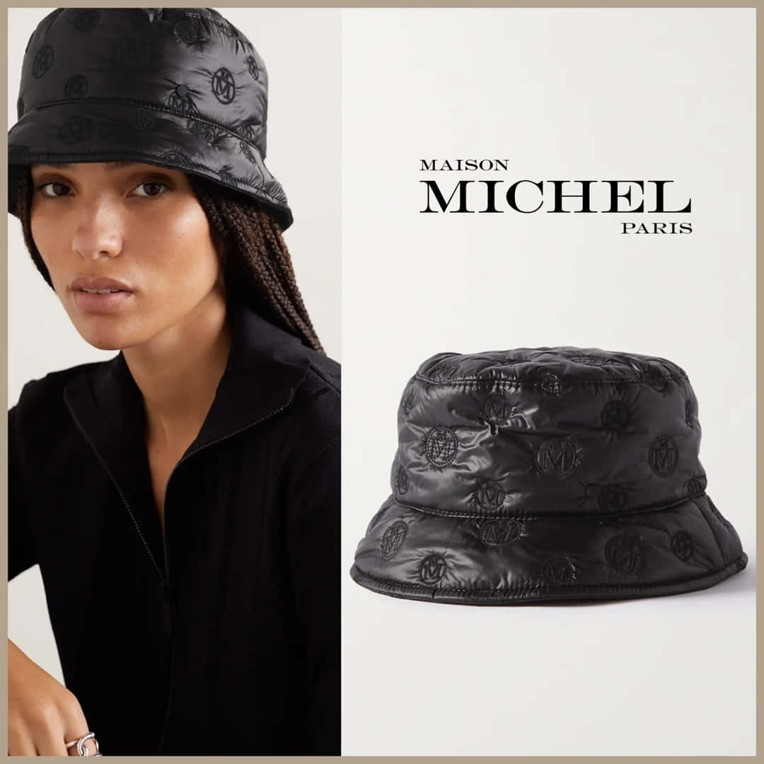 Maison Michel 品牌標誌與模特兒 壁紙 — 一位模特兒戴著黑色絎縫水桶帽，上面有重複的標誌圖案，而產品照片則顯示同一頂帽子在純白色背景上。