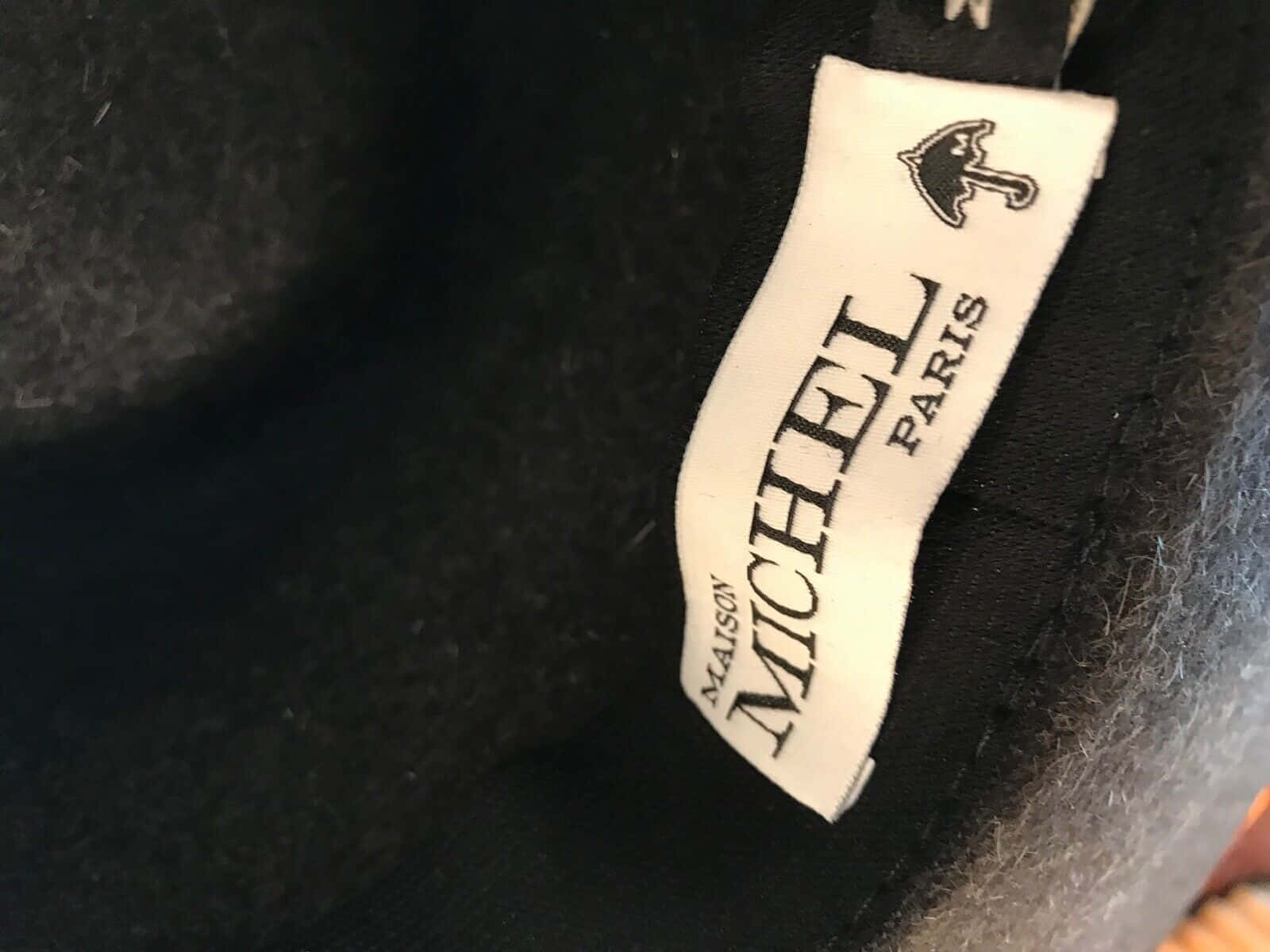 Maison Michel Paris 服裝標籤的特寫，深色羊毛上有雨傘標誌。