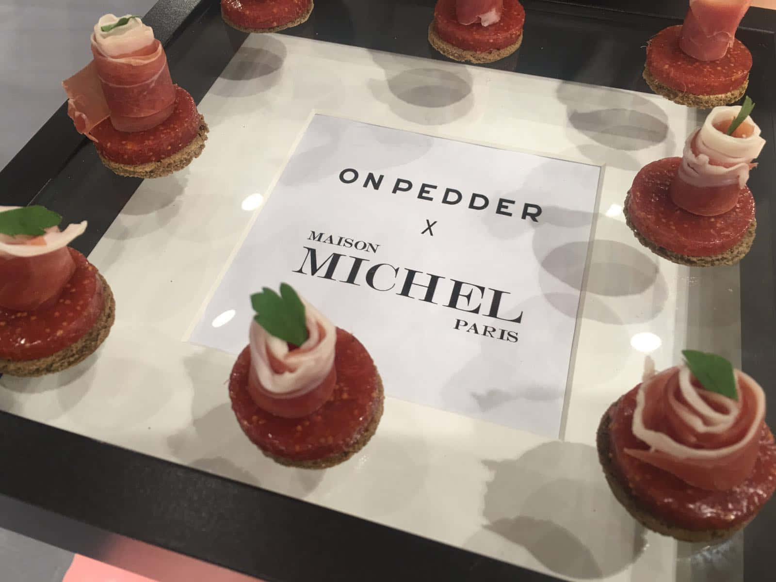 美食小點搭配帕爾瑪火腿和無花果果醬，圍繞品牌卡片展示。