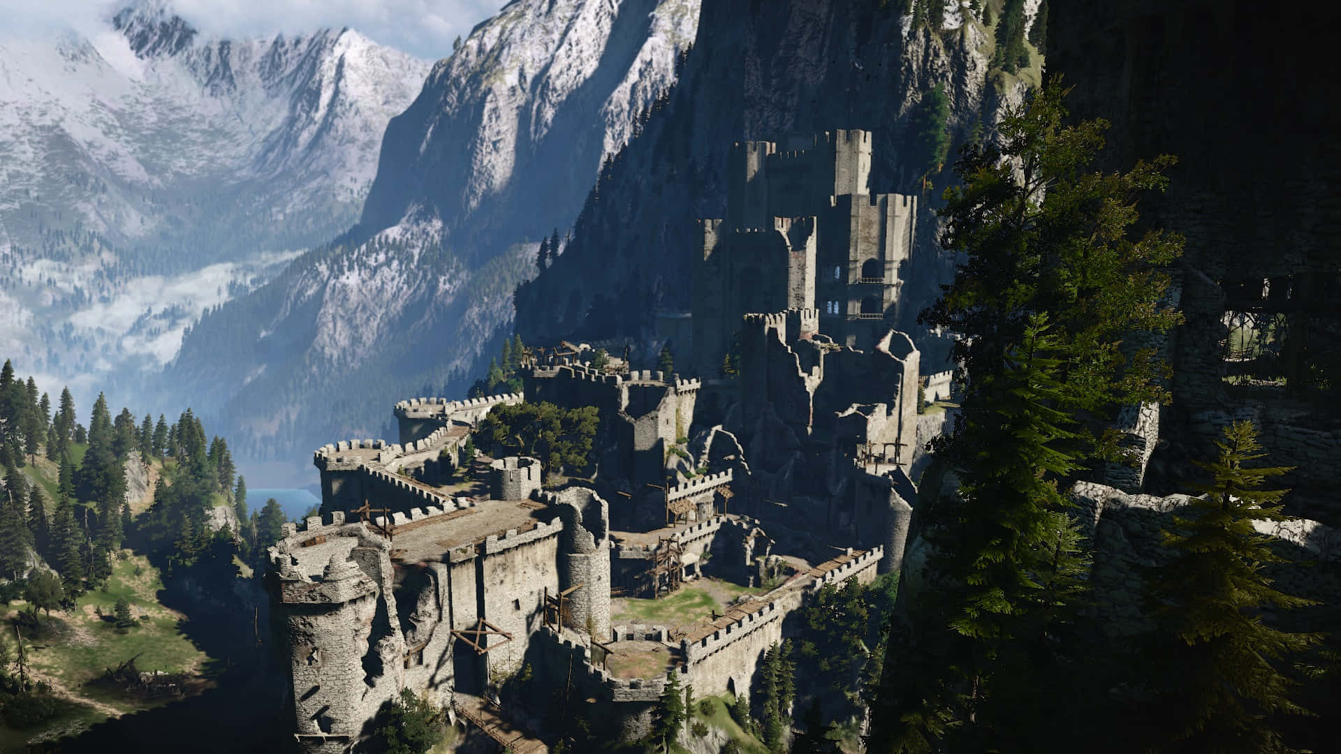 Kaer Morhen 桌布 壁紙 — 一座雄偉的石城堡坐落在懸崖上，俯瞰著山谷，山谷中有白雪覆蓋的山脈和茂密的松林，天空明亮。