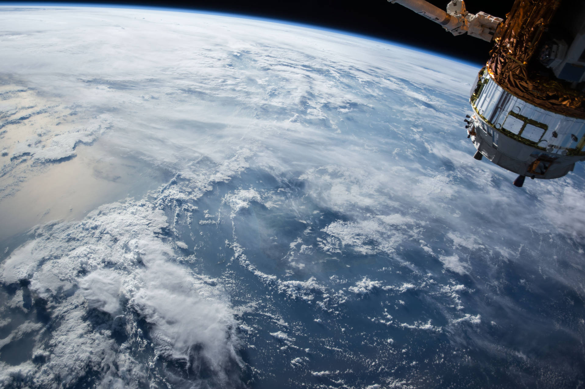 從太空俯瞰地球的壯麗景色 壁紙 — 一艘太空船從太空懸浮在地球旋轉的藍色海洋和白色雲層之上。