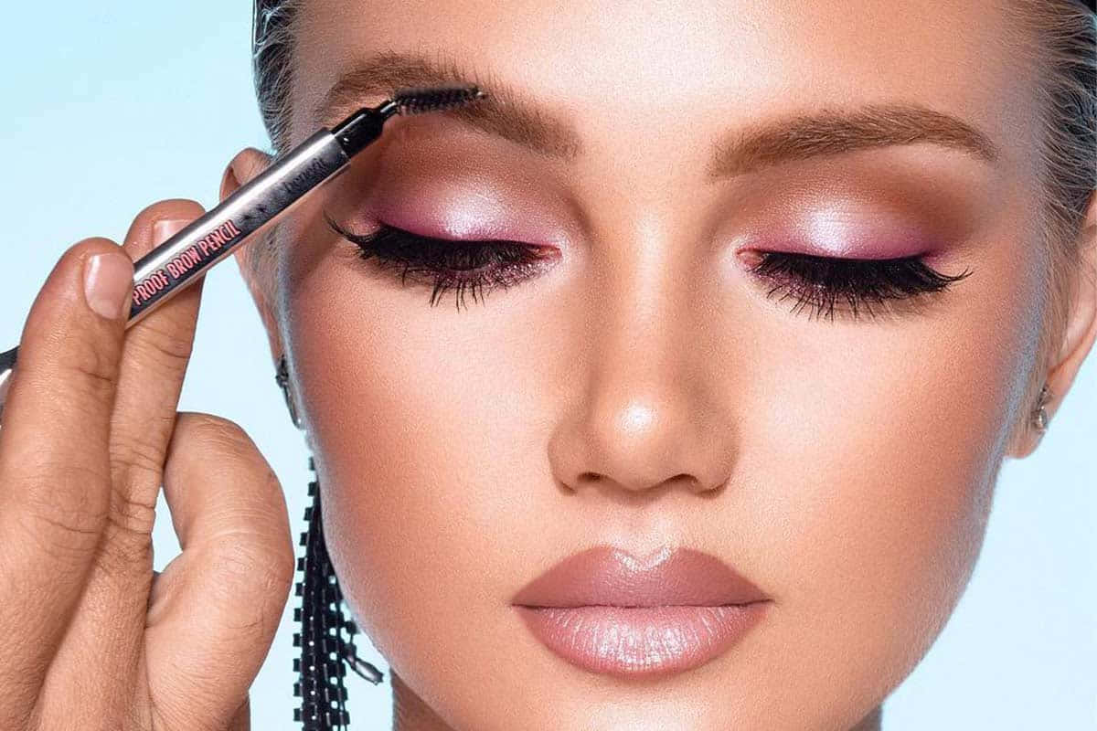 女士用粉紅色眼影和光澤嘴唇畫眉筆。