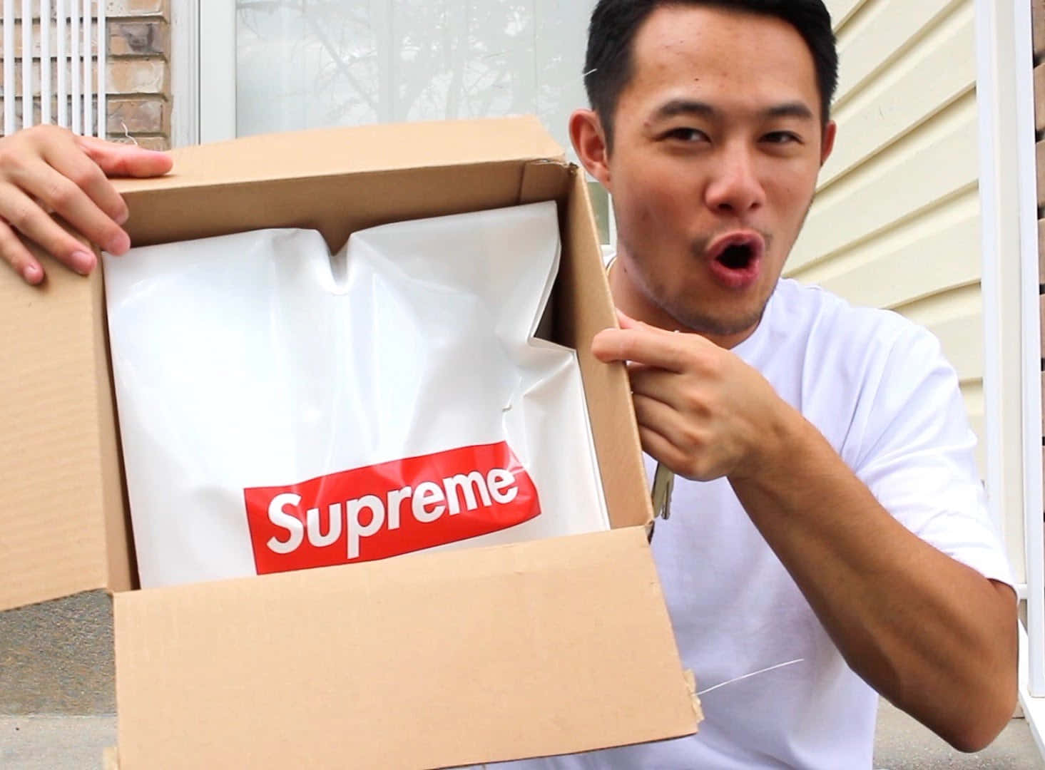 男子在屋外興奮地打開Supreme襯衫盒。