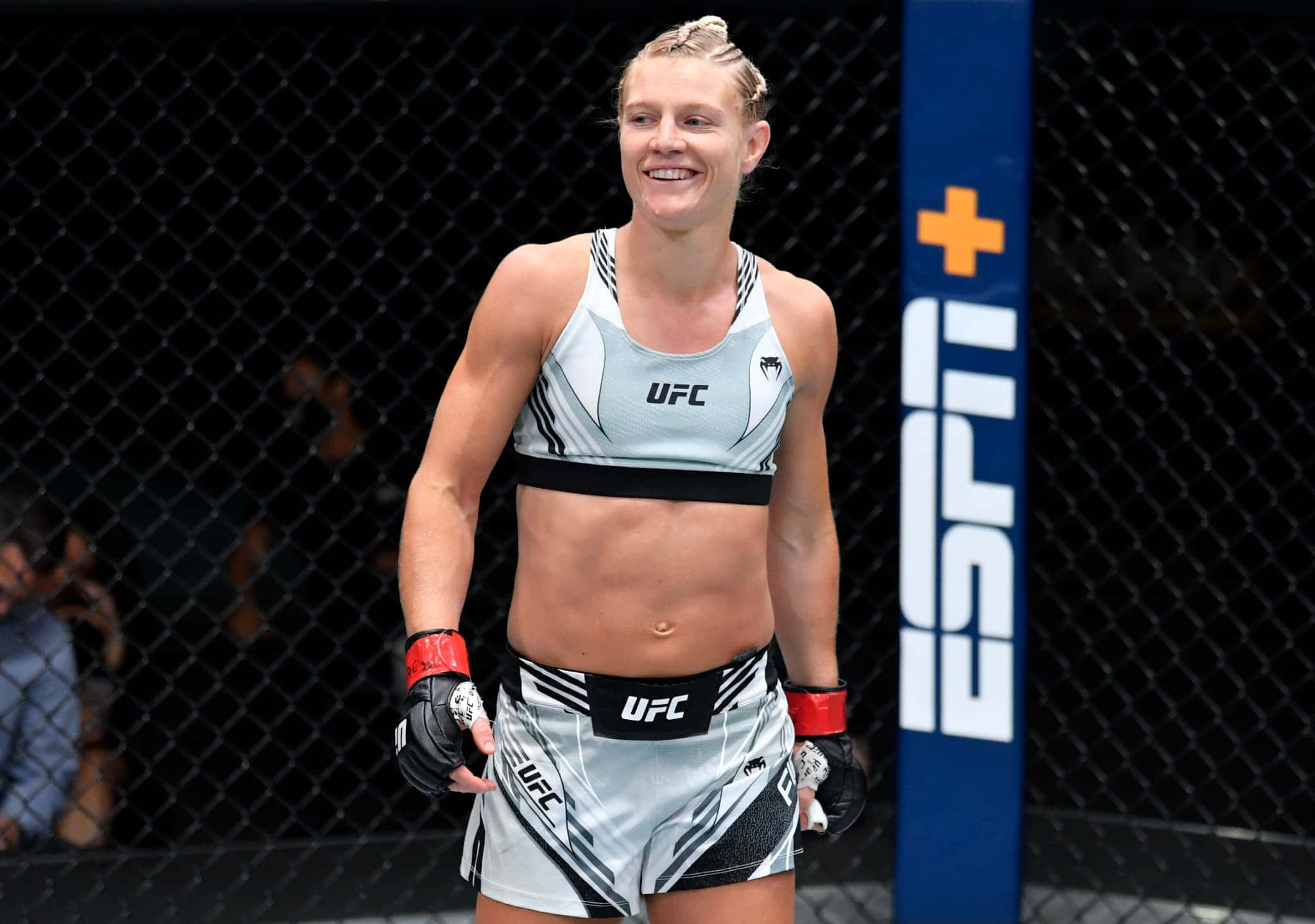 Manon Fiorot 自信滿滿 壁紙 — 一位微笑的女MMA拳手穿著UFC裝備，自信地站在八角籠內，ESPN+品牌標誌清晰可見。