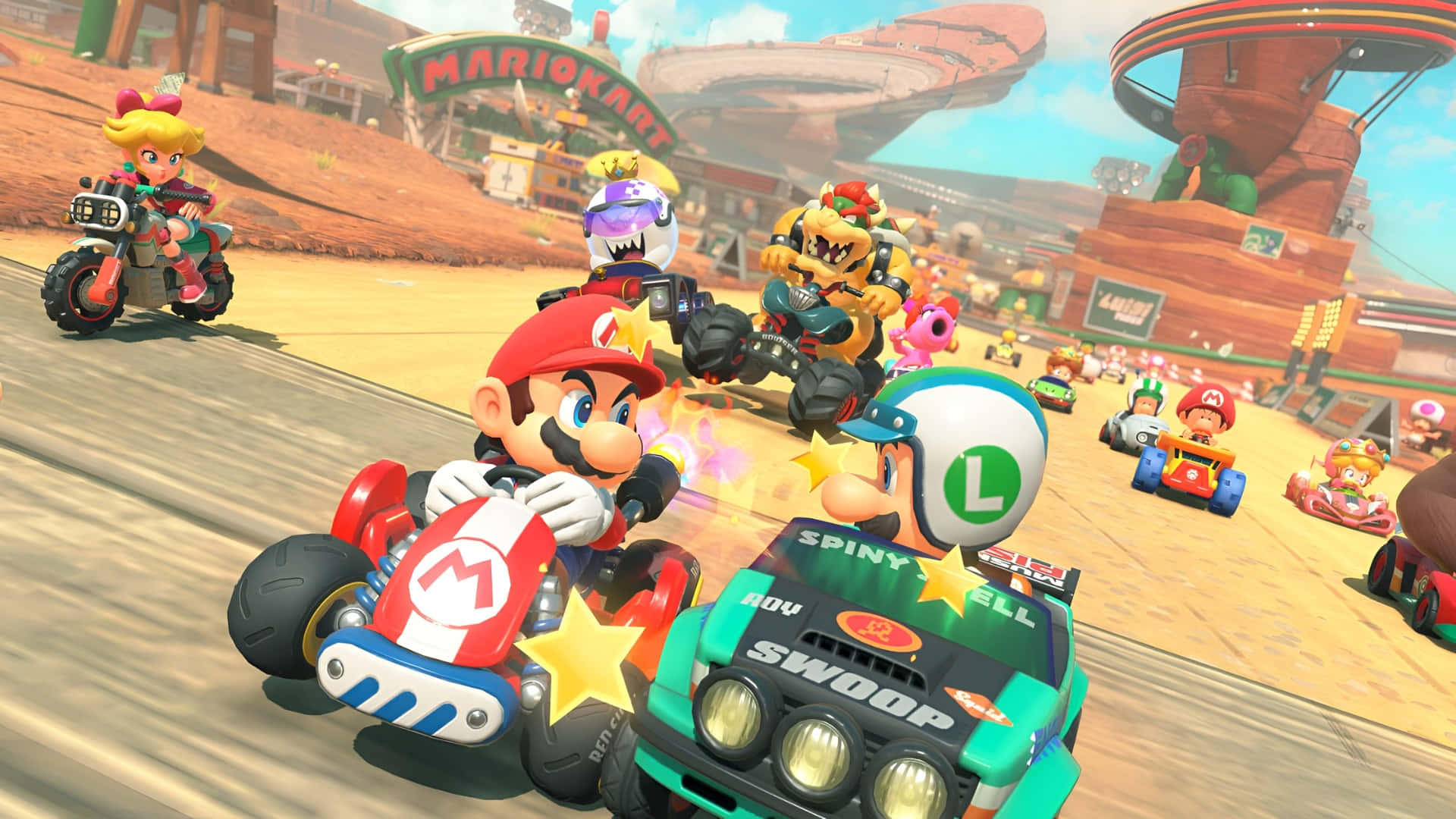  壁紙 — Mario 在充滿活力的沙漠卡丁車賽道上比賽，伴隨著色彩繽紛的角色和動態運動模糊效果。