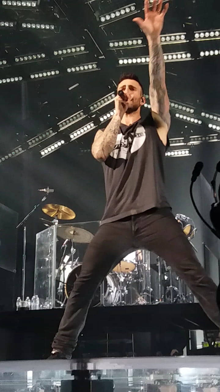有紋身的男歌手在明亮的燈光下在舞台上表演。