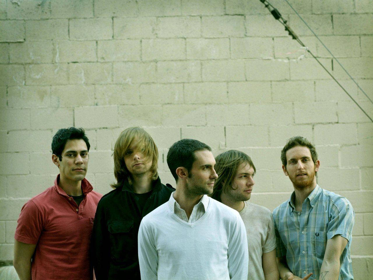 Maroon 5 白色磚牆集體照 壁紙 — 五個穿著休閒服的男人在柔和日光下靠著一面風化的混凝土塊牆站立。